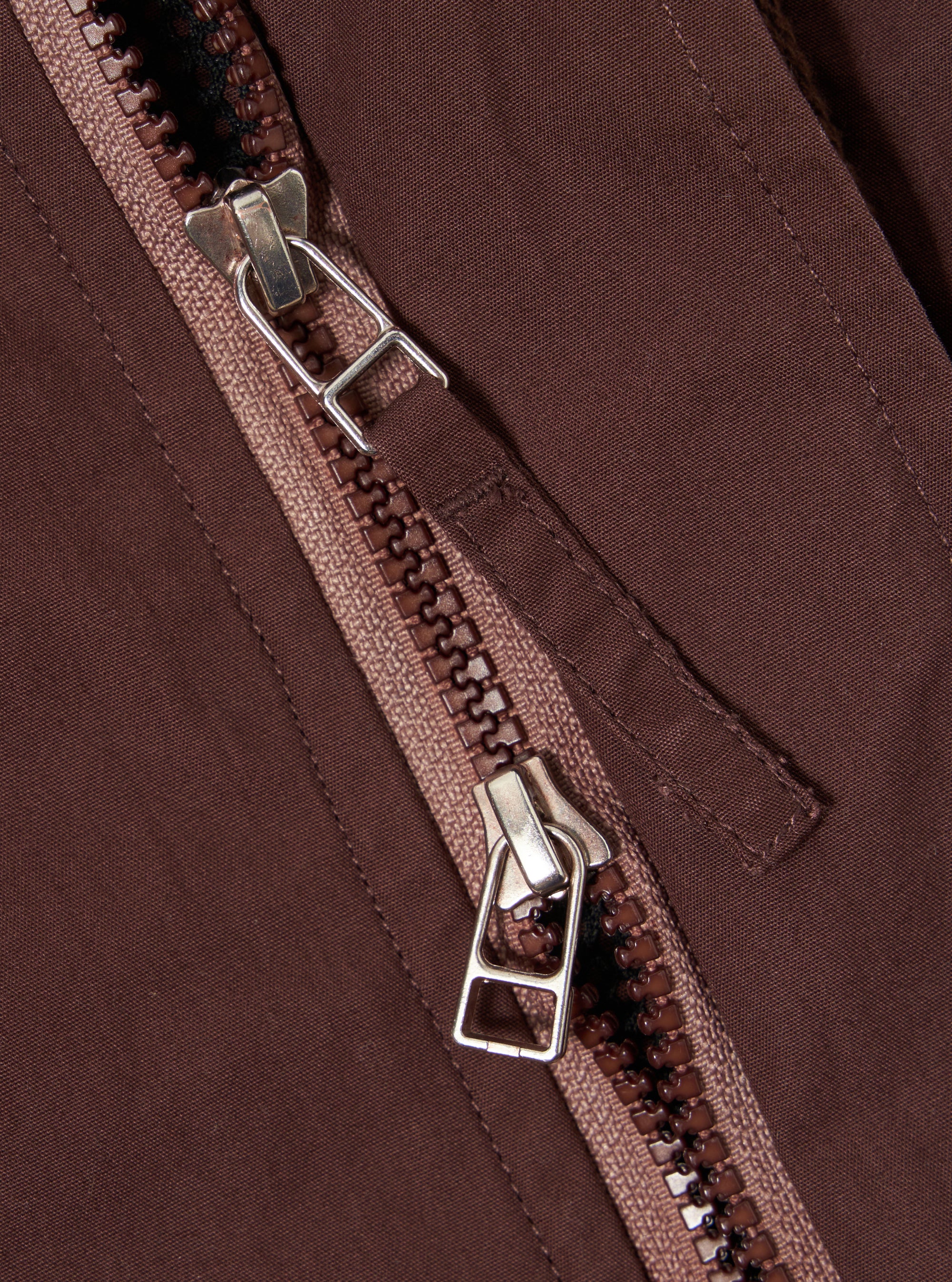 The Brown Peached Poplin NS Bomber Jacket is shown from the back as a flat lay against a plain white background. The image highlights the clean, simple construction of the garment's rear panel, featuring a ribbed collar and set-in sleeves. The peached cotton poplin fabric has a smooth, matte brown finish.