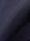 A close-up fabric swatch of the Navy Peached Poplin NS Bomber Jacket highlights the smooth, matte texture and deep navy blue color of the peached poplin material. The fabric fills the frame, providing a detailed view of the garment's weave and finish.