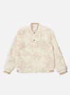 The Ecru 3D Flower NS Bomber Jacket is shown as a flat lay against a plain white background. The jacket features an intricate all-over 3D floral texture in an ecru shade, a central two-way zip closure with a buttoned placket, and contrast stripe ribbing on the collar, cuffs, and hem. A prominent zipped utility stash pocket is visible on the left sleeve.