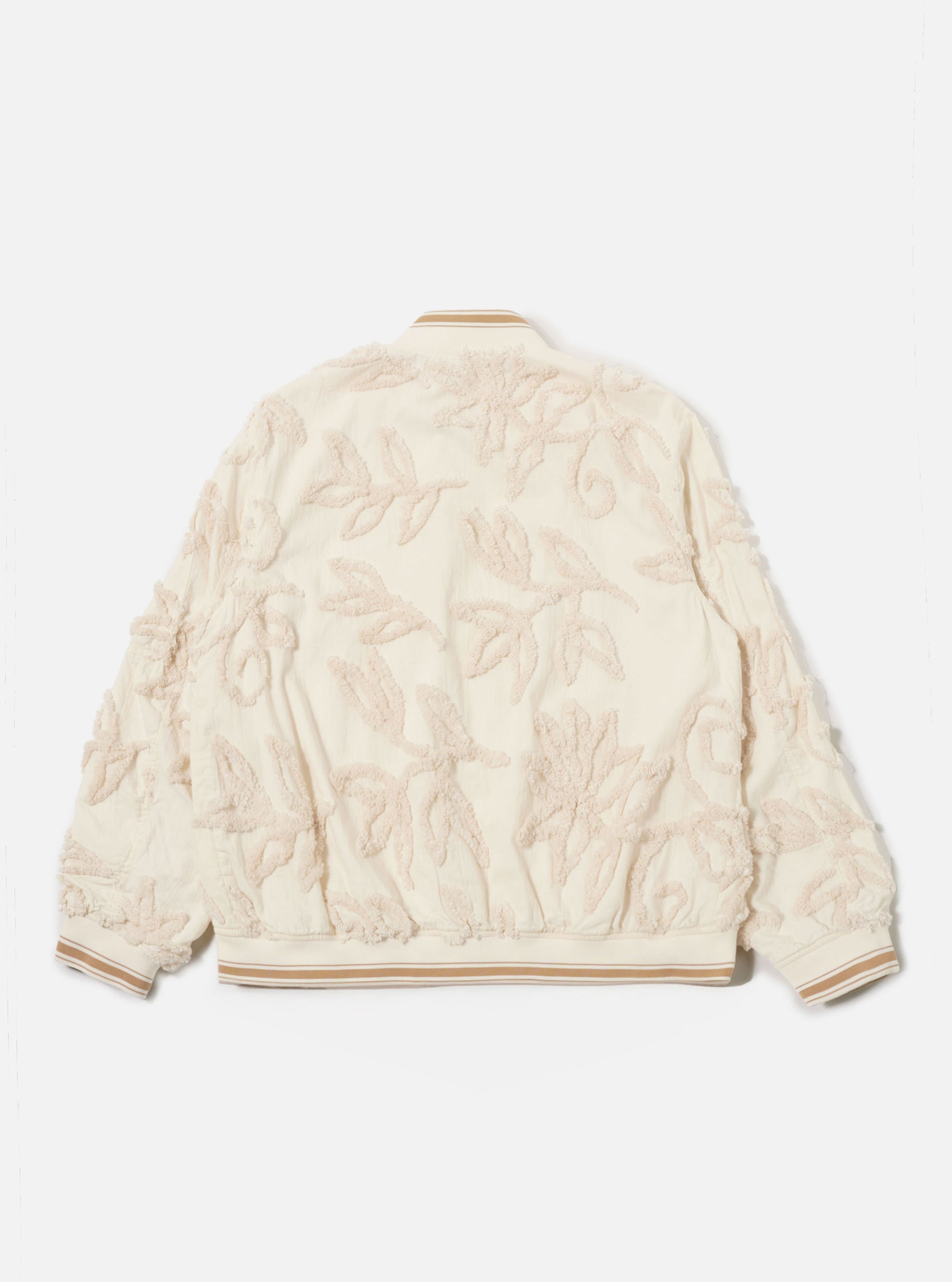 The Ecru 3D Flower NS Bomber Jacket is shown from the back as a flat lay against a plain white background. The jacket features an all-over textured 3D flower pattern on ecru fabric, accented by contrast stripe ribbing on the collar and hem. The image highlights the articulated sleeve construction and the clean, straight hem.