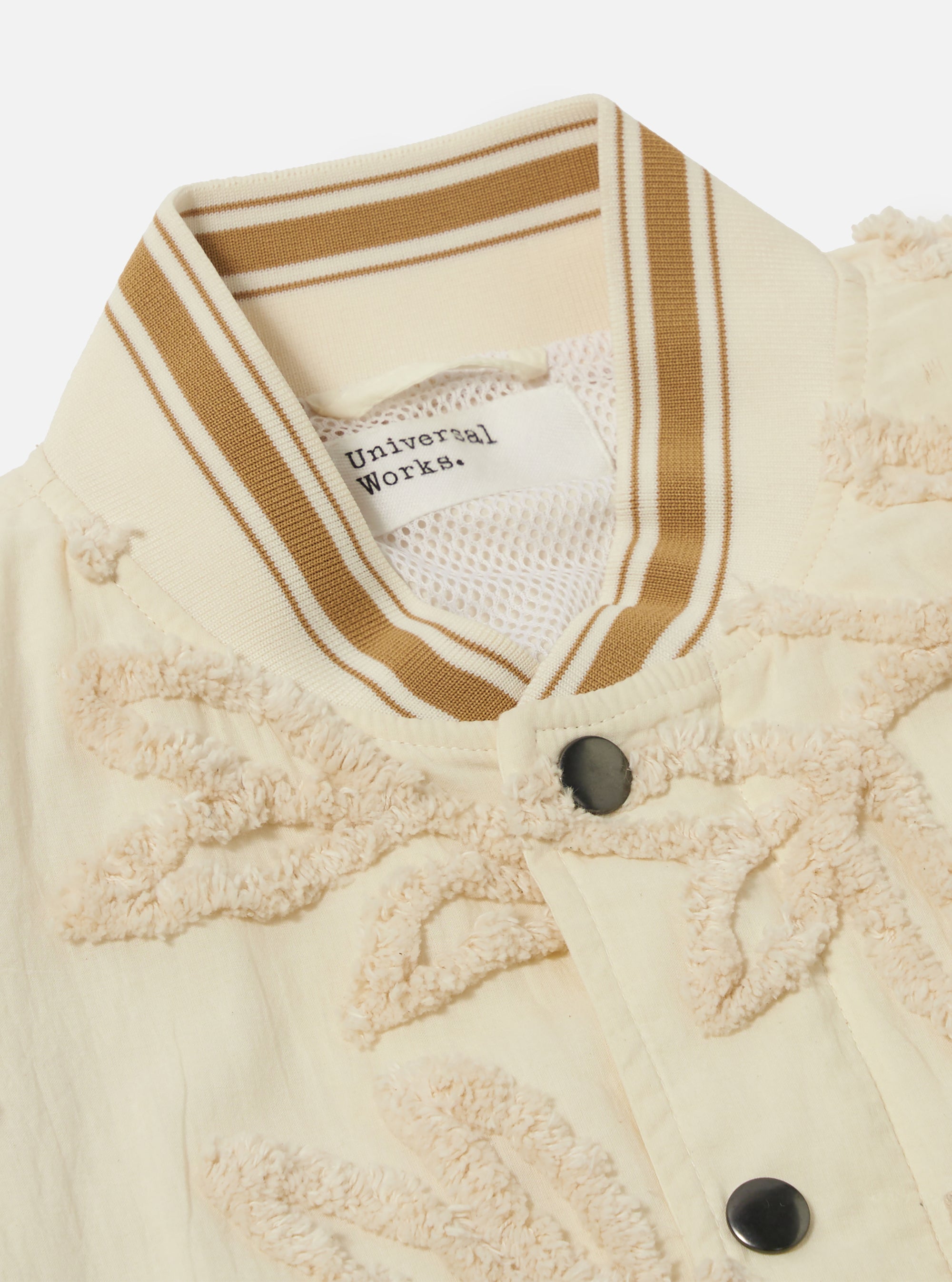 The Ecru 3D Flower NS Bomber Jacket is shown from the back as a flat lay against a plain white background. The image highlights the intricate 3D floral texture of the ecru fabric, the contrast stripe ribbing on the collar and hem, and the articulated sleeve construction.