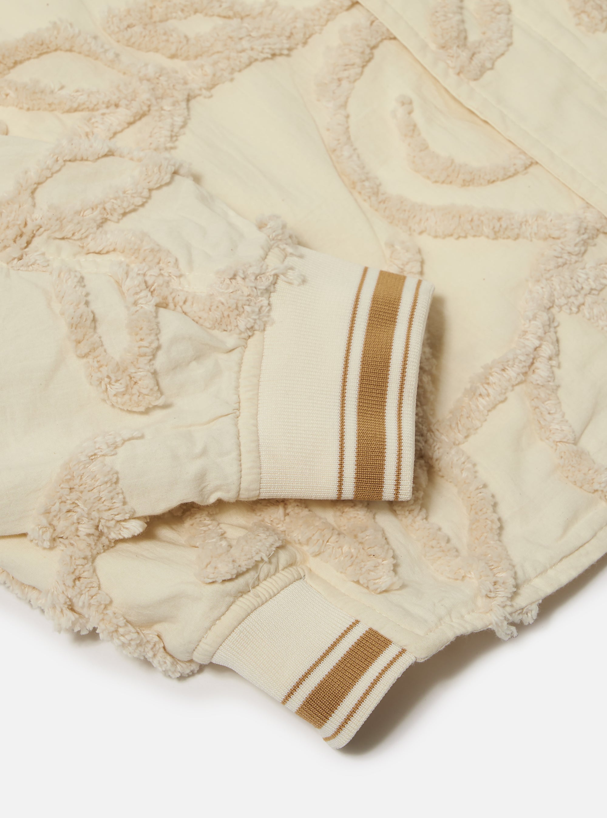 The Ecru 3D Flower NS Bomber Jacket is shown from the back as a flat lay against a plain white background. The jacket features an all-over textured 3D flower pattern in an ecru color, with contrasting striped ribbing on the collar, cuffs, and hem.