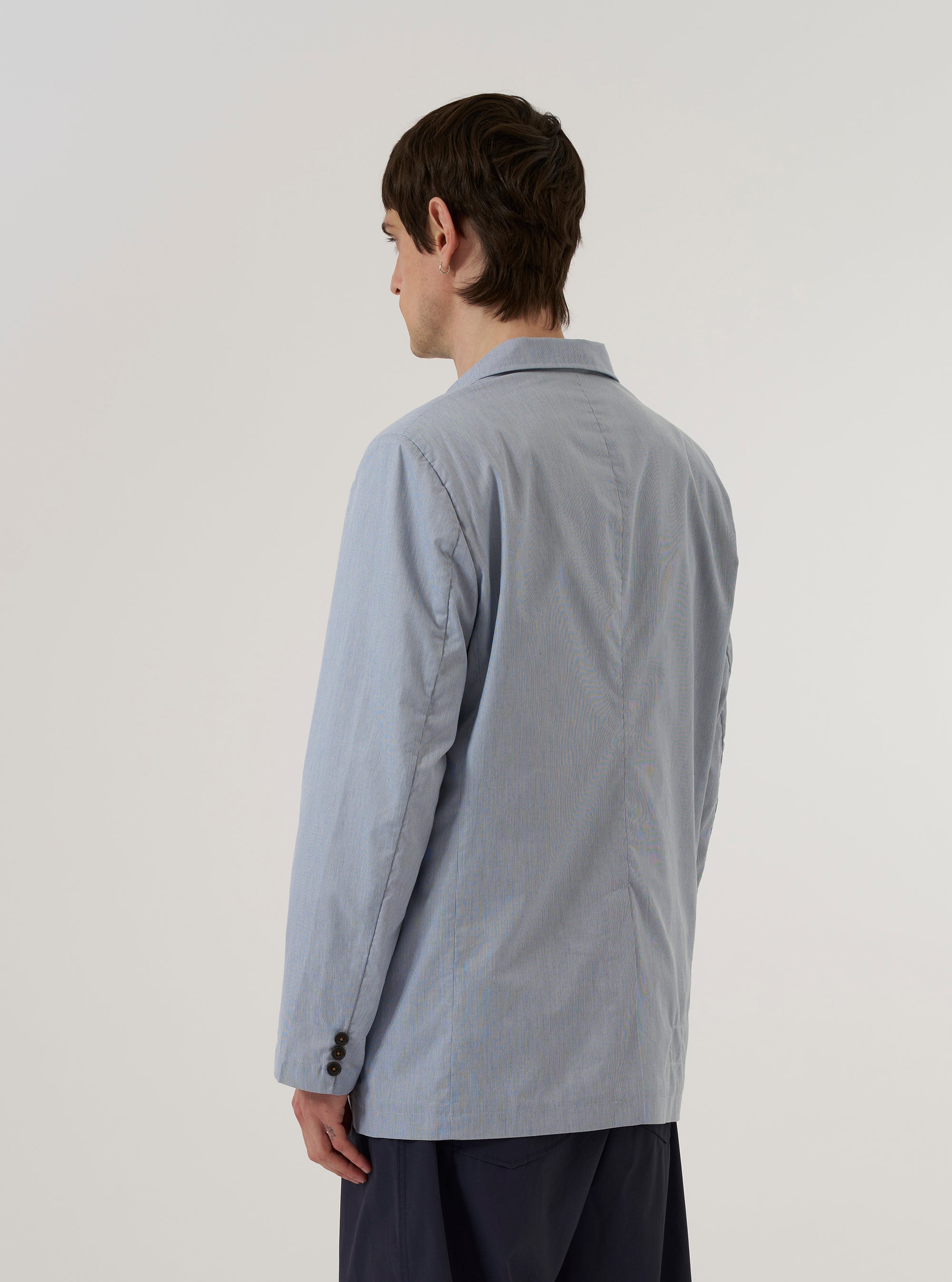 A model wears the Navy Kennedy Stripe Boston Blazer, shown from the back against a plain white background. The blazer features a subtle vertical pinstripe pattern on a navy blue cotton fabric, a single vent at the hem, and a structured, tailored fit. No mannequin is present in the image.