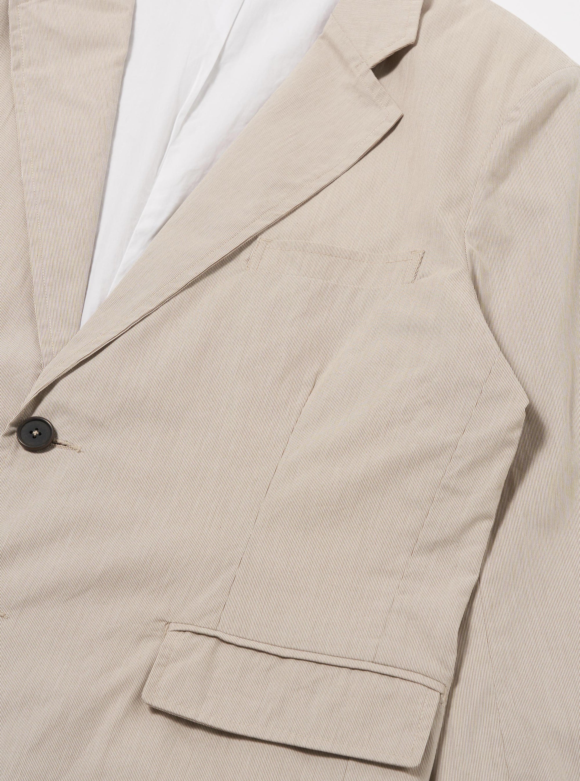 The Brown Kennedy Stripe Boston Blazer is shown in a detail view as a flat lay against a plain white background. The image focuses on the lower front section of the garment, highlighting a large patch pocket and the distinct brown and cream vertical stripe pattern of the cotton fabric.