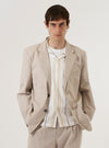 A model wears the Brown Kennedy Stripe Boston Blazer over a dark top, standing against a plain, light-colored background. The blazer features a notched lapel, a three-button front closure, and two large patch pockets at the waist. The brown fabric is characterized by a distinct vertical stripe pattern throughout.