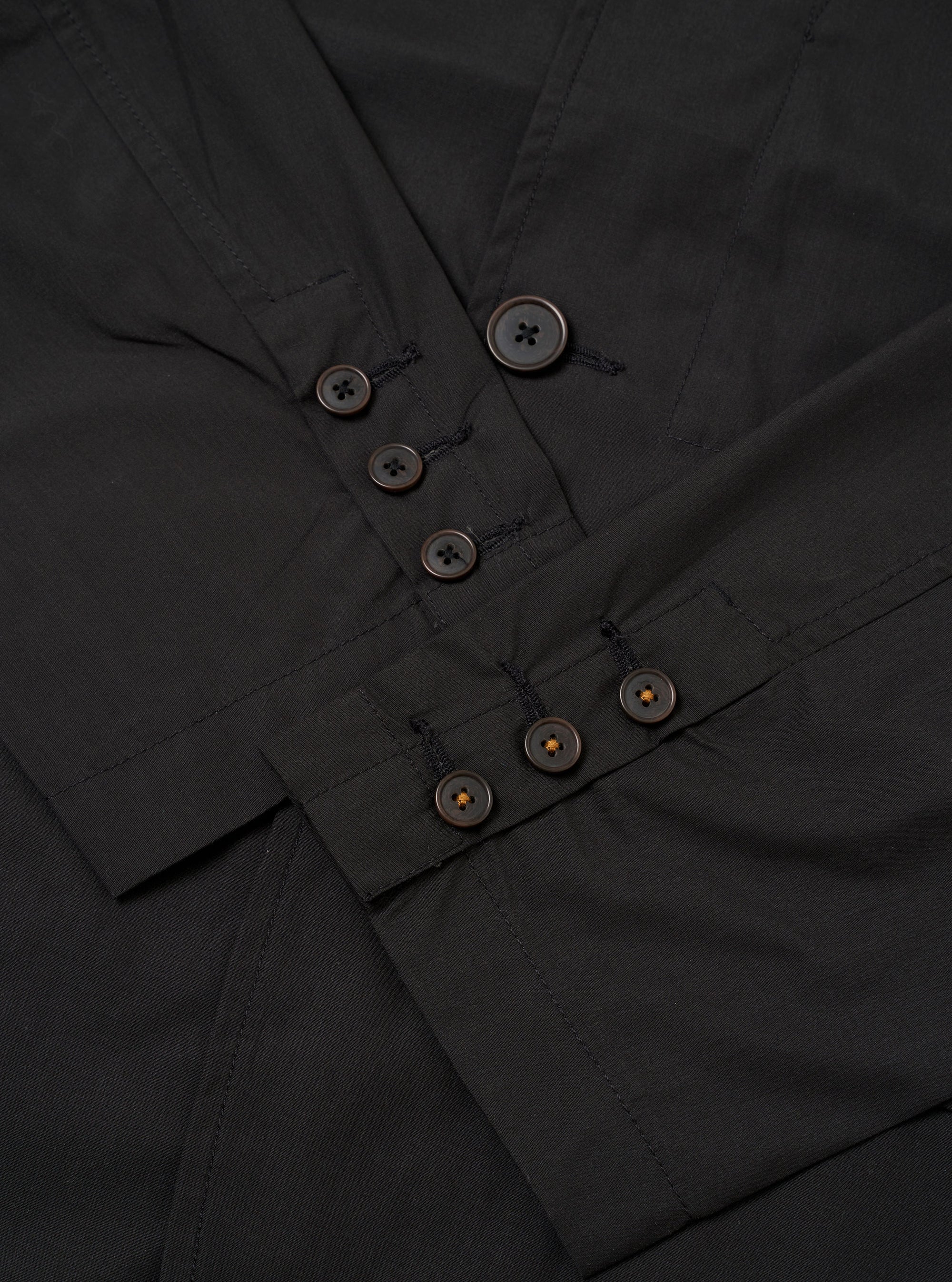The Black Recycled Polytech Capitol Jacket is shown in a close-up detail shot as a flat lay against a plain white background. The image focuses on the lower front section of the garment, highlighting a large patch pocket with a flap closure and the smooth, technical texture of the black recycled polytech fabric. Clean tonal stitching and a straight hem are visible.