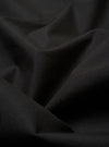 The Black Recycled Polytech Capitol Jacket is shown from a rear three-quarter angle as a flat lay against a plain white background. The image highlights the jacket's unstructured design, featuring a single back vent and a smooth black fabric with a subtle technical sheen.
