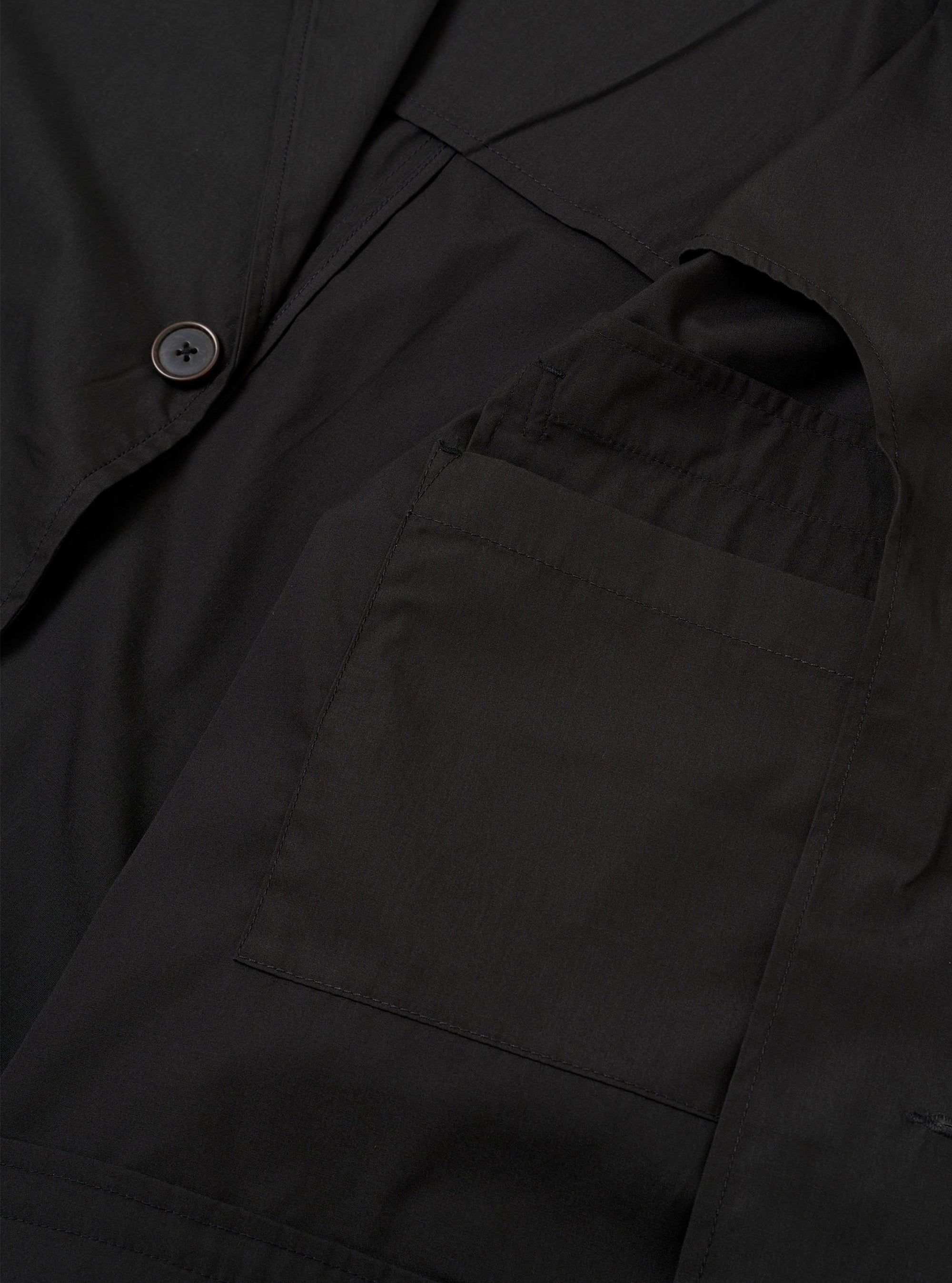 The Black Recycled Polytech Capitol Jacket is shown in a detail view as a flat lay against a plain white background. The image highlights the smooth, technical texture of the black recycled polytech fabric and the construction of the front patch pocket with a flap.