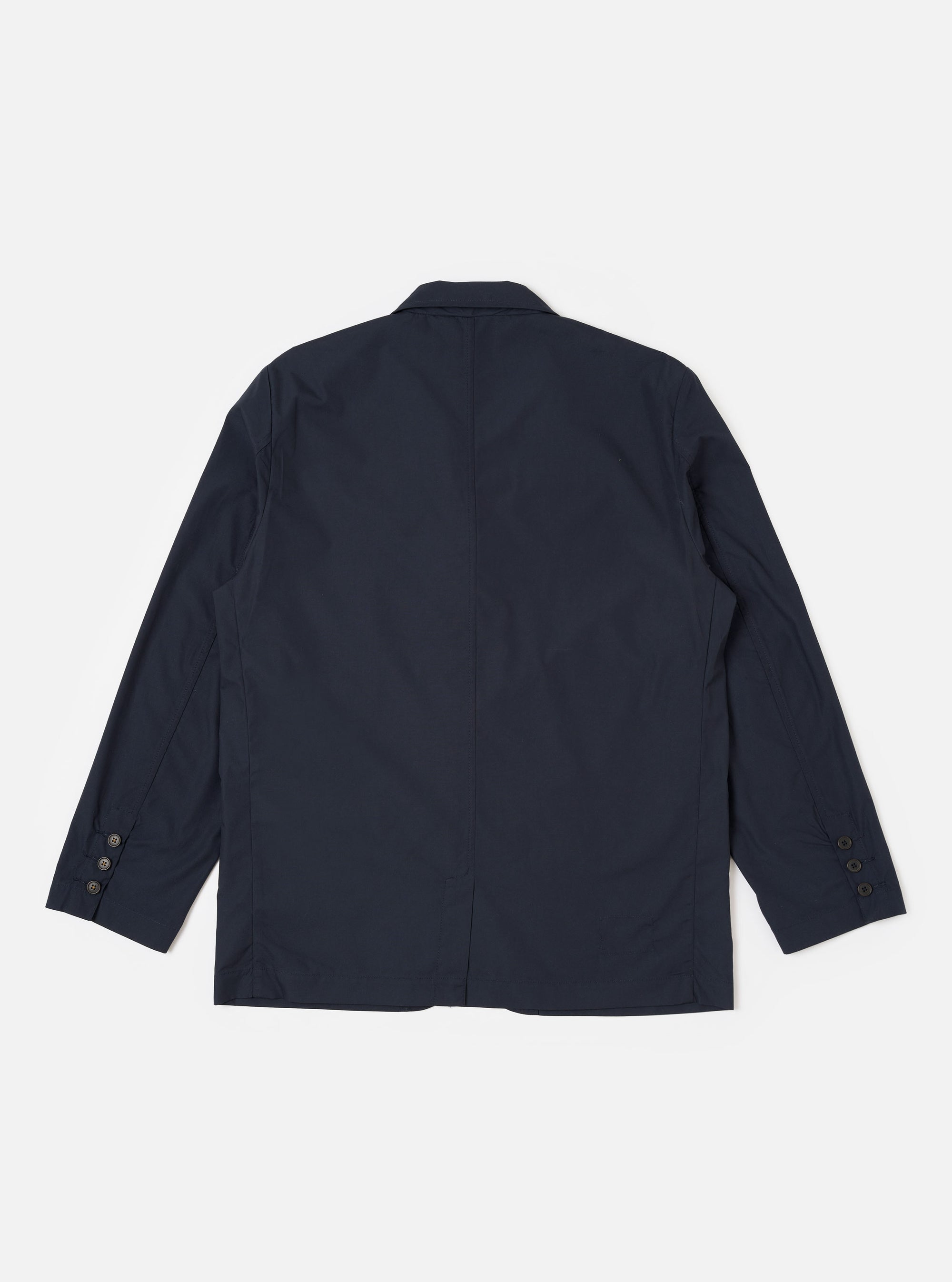 The Navy Recycled Polytech Capitol Jacket is shown from the back as a flat lay against a plain white background. The jacket features a clean, structured back with a visible seam running vertically down the center and a small rectangular patch detail near the neck. The hem and cuffs are simple and finished.
