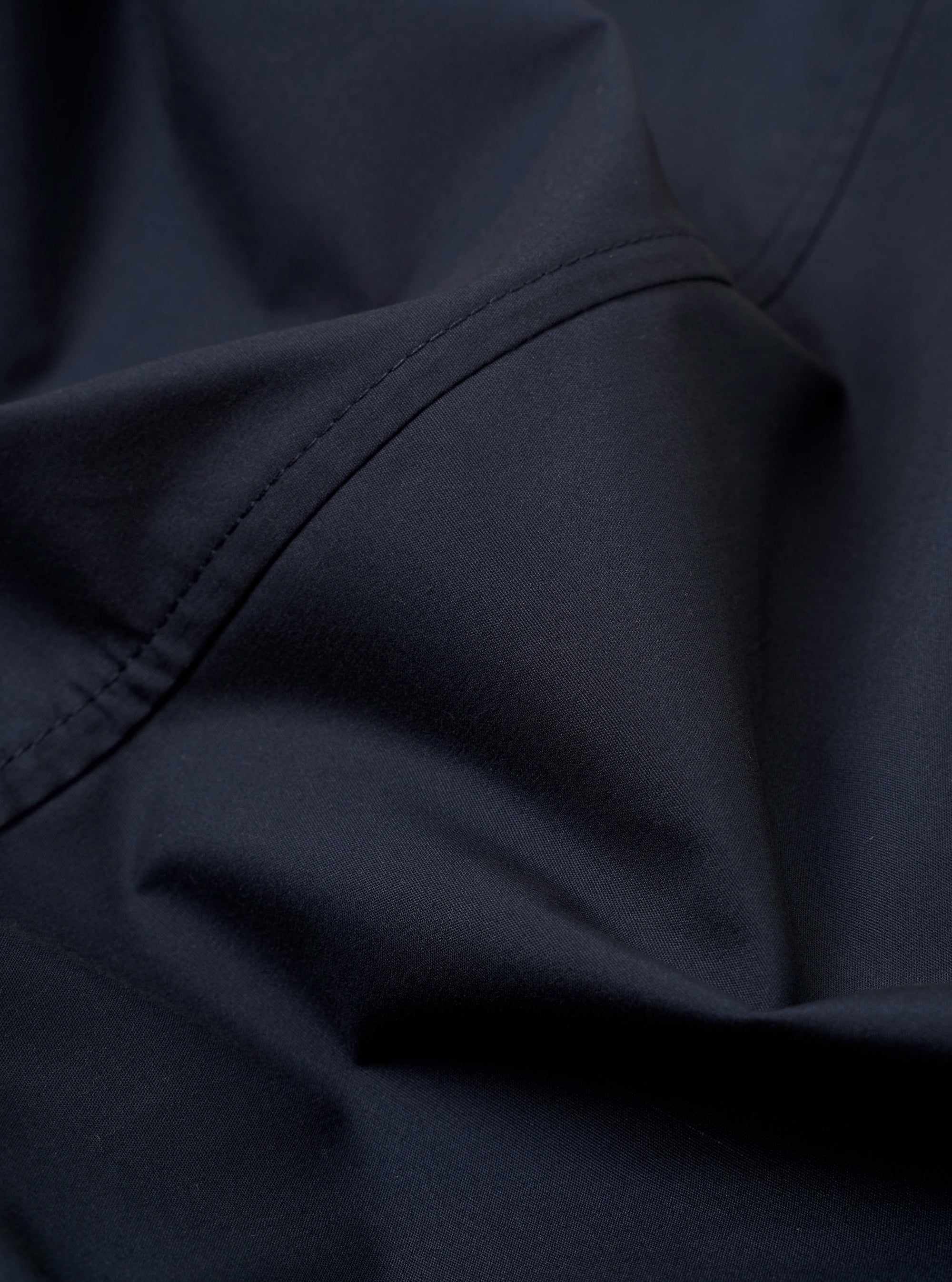 The Navy Recycled Polytech Capitol Jacket is shown from the back as a flat lay against a plain white background. The image highlights the clean construction of the shoulders, the straight hem, and the smooth texture of the recycled fabric.