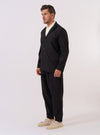The Black Recycled Polytech Capitol Jacket is shown as a flat lay against a white background. The jacket features a notch lapel, a three-button front closure, and four front pockets with flap closures. The recycled polytech fabric has a smooth, matte finish.