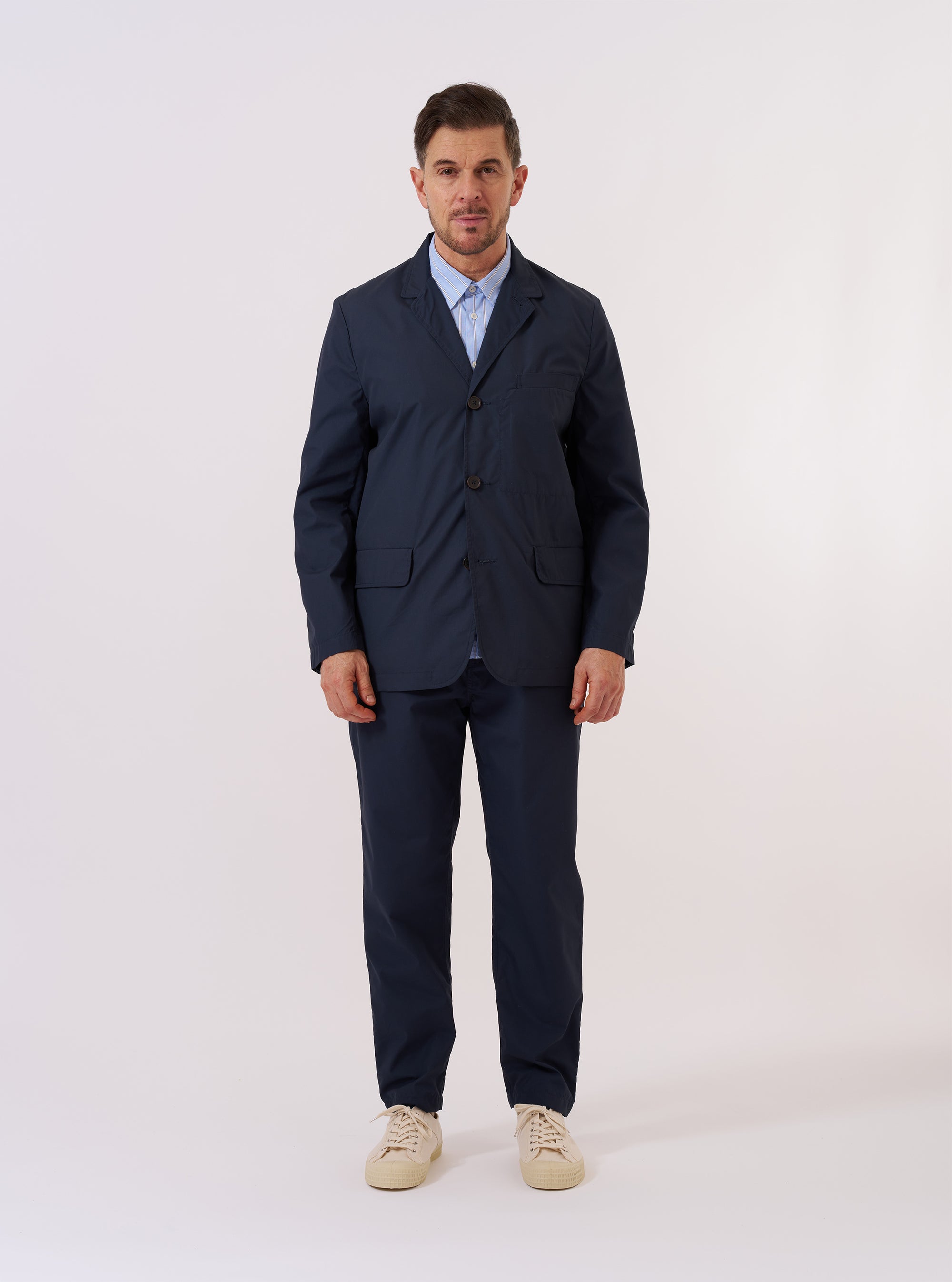 The Navy Recycled Polytech Capitol Jacket is presented as a flat lay against a plain white background. The jacket features a three-button front, a notched lapel with a buttonhole, one chest welt pocket, and two lower flap pockets. The fabric is a smooth, solid navy blue.