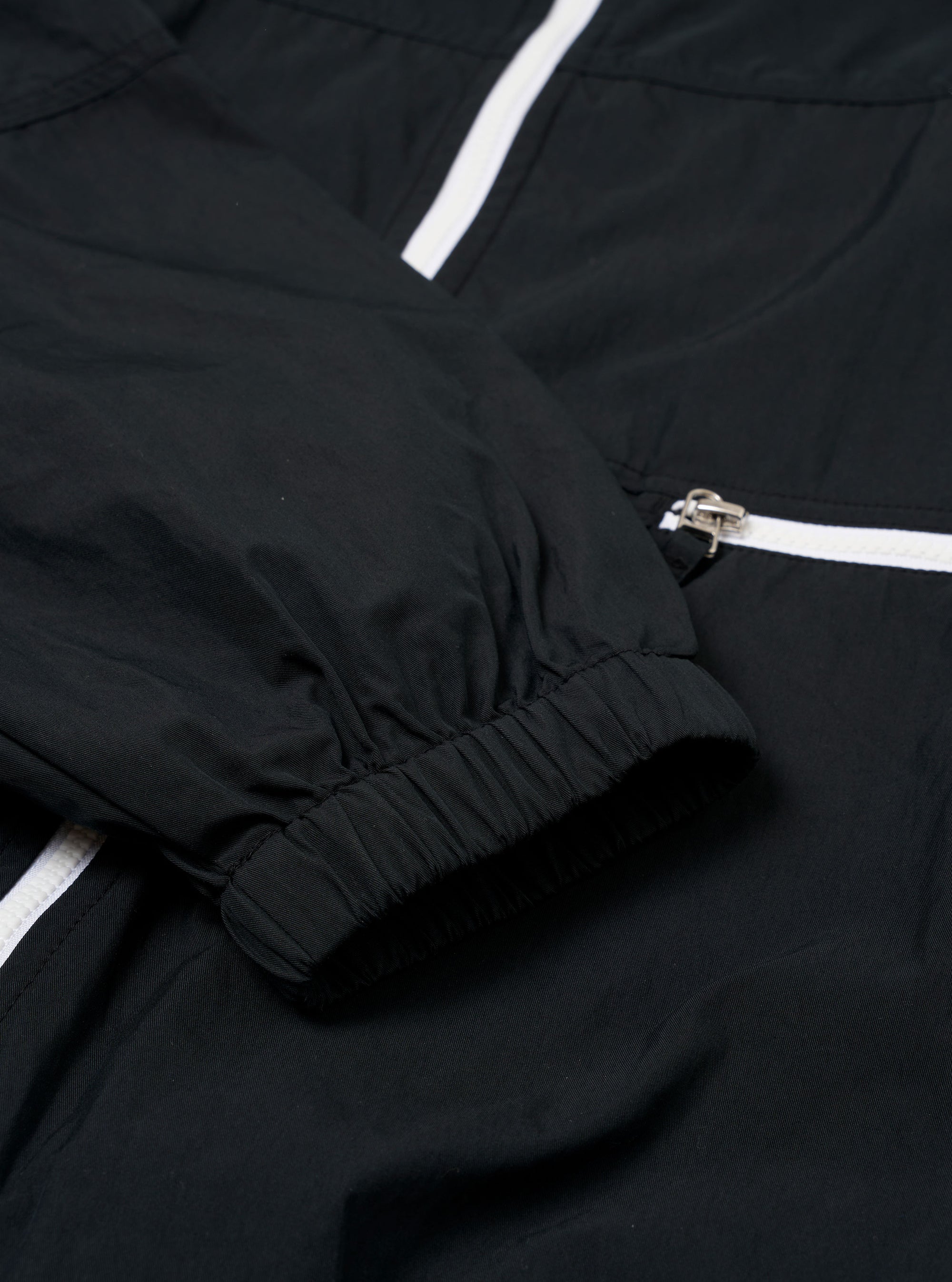 The Navy Cotton Recycled Nylon Mix Daley Jacket is shown in a detail view as a flat lay against a plain white background. This close-up highlights the lower portion of the jacket, featuring a zipped hand warmer pocket and the structured hemline. The fabric has a smooth, matte finish.