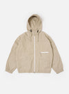 The Sand Cotton Recycled Nylon Mix Daley Jacket is shown as a flat lay against a white background. The jacket features a central zip front, a stand-up collar, and two large zipped patch pockets at the waist. The fabric is a smooth, sand-colored cotton and recycled nylon blend with visible panelling details.