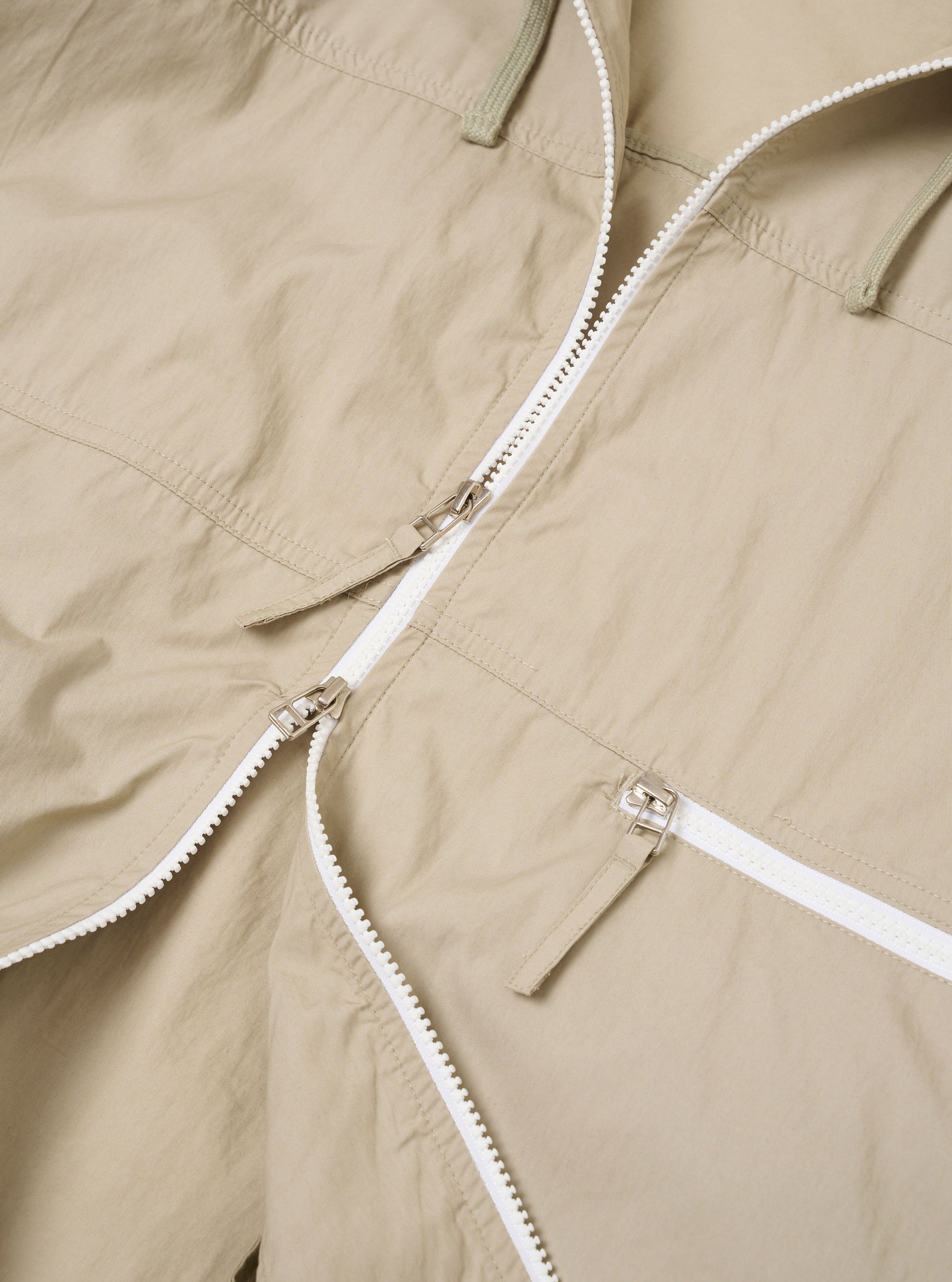 The Sand Cotton Recycled Nylon Mix Daley Jacket is shown from a rear angle as a flat lay against a plain white background. The jacket features a large hood, a straight hem, and a clean back panel construction. The sand-colored fabric has a smooth, matte finish.
