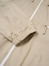 The Sand Cotton Recycled Nylon Mix Daley Jacket is shown in a detail view as a flat lay against a plain white background. The image highlights the technical texture of the sand-colored fabric and the construction of the adjustable drawstring hood and the central zip-front closure.