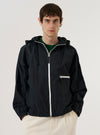 A model wears the Navy Cotton Recycled Nylon Mix Daley Jacket against a plain white background. The jacket is a hooded zip-up style featuring a central zipper, a drawstring hood, and two large patch pockets at the waist. The model is shown from the front, wearing the jacket over a light-colored top. The fabric has a smooth, matte finish.