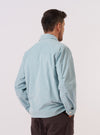 The Aqua Organic Fine Cord Duty Jacket is shown from the back, worn by a model against a plain white background. The image highlights the straight hem, a single vertical seam down the center of the back, and the fine-ribbed texture of the aqua-colored corduroy fabric. The model's hands are visible at their sides.