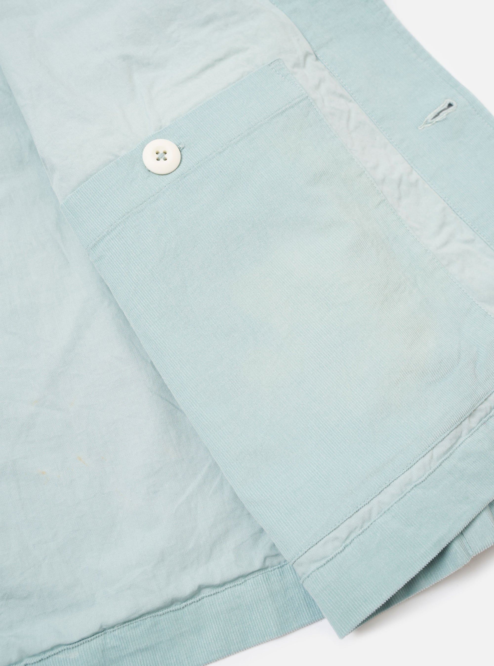 The Aqua Organic Fine Cord Duty Jacket is shown from the back as a flat lay against a plain white background. The jacket features a clean back panel with a horizontal yoke across the shoulders and a straight hem. The fine-ribbed texture of the aqua-colored organic cotton corduroy is visible throughout the garment.