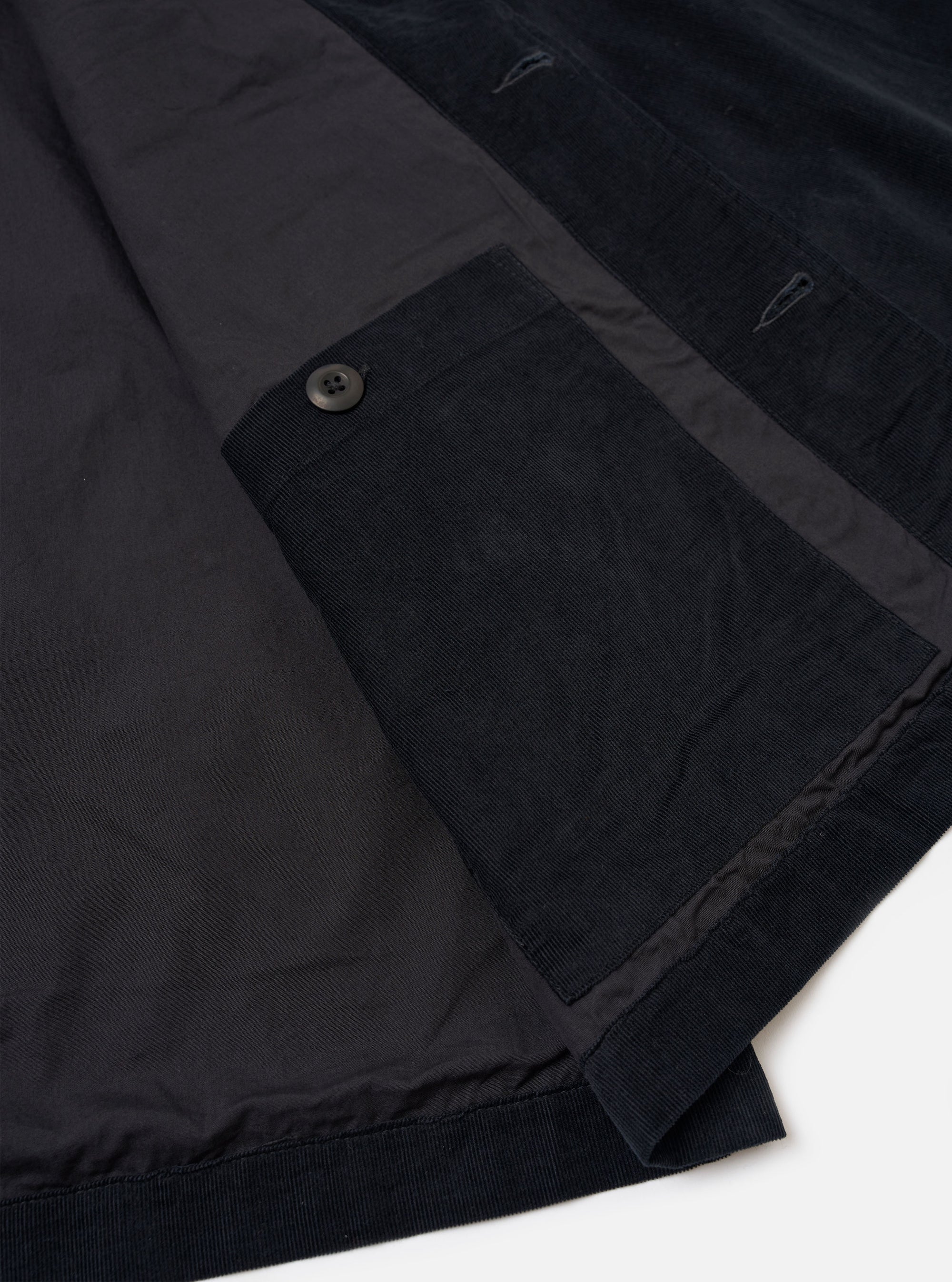 The Black Organic Fine Cord Duty Jacket is shown from the back as a flat lay against a plain white background. The image highlights the jacket's curved hem, back yoke detail, and the fine texture of the black corduroy fabric.