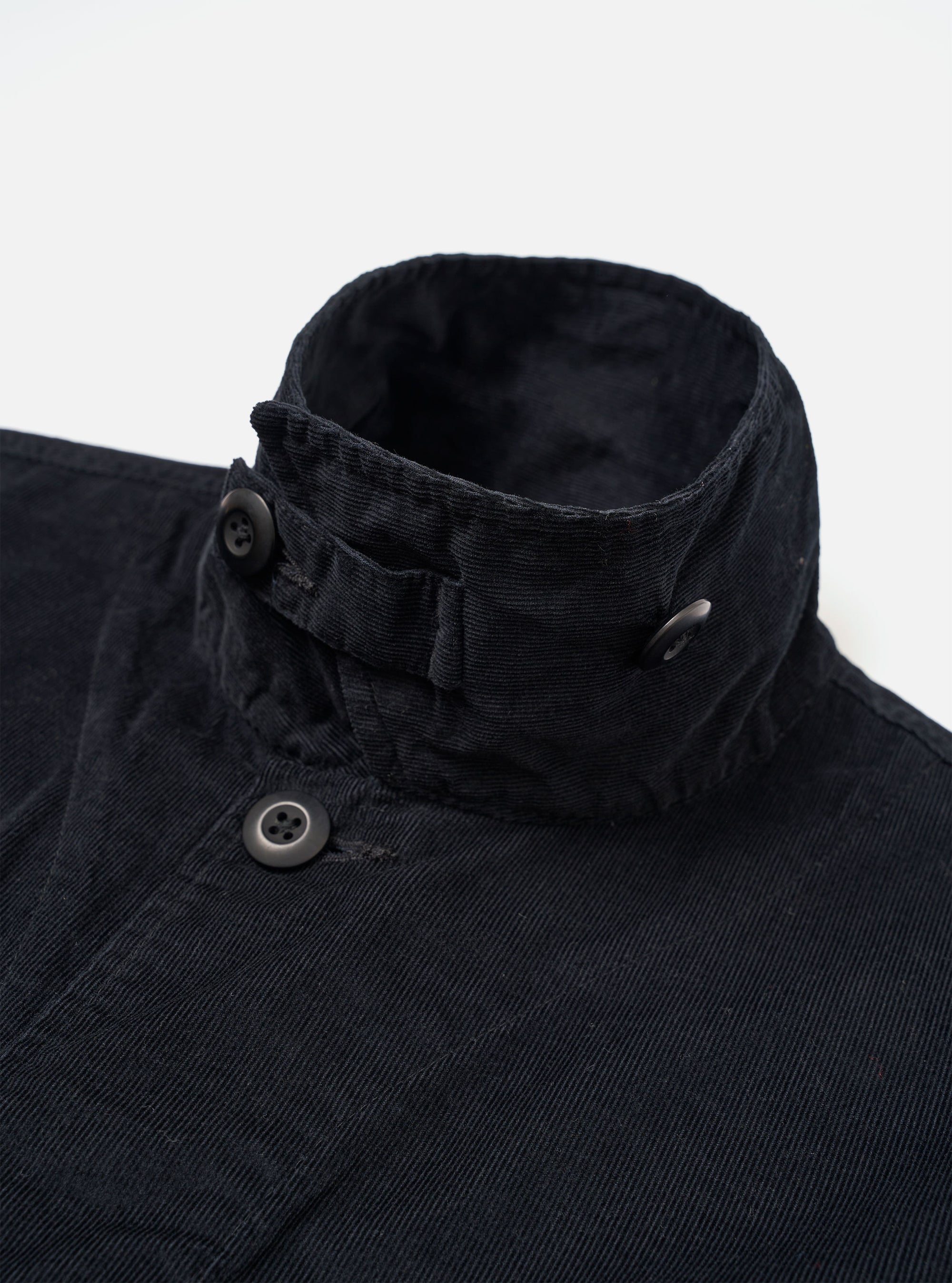 The Black Organic Fine Cord Duty Jacket is shown from the back as a flat lay against a white background. The image highlights the center back seam, the straight hem, and the fine-waled texture of the black corduroy fabric.