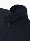 The Dark Navy Ospina Cotton Duty Jacket is shown from a rear three-quarter angle as a flat lay against a plain white background. The image highlights the jacket's oversized fit, loose darted sleeves, and curved hem. The dark navy fabric features a visible puckered seersucker texture.