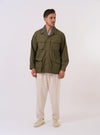 The Olive Recycled Polytech Jungle Jacket is shown as a flat lay against a white background. The jacket features a concealed button front placket and four large 3D pleated pockets with concealed button-down flaps. It has a structured collar and adjustable cuffs.