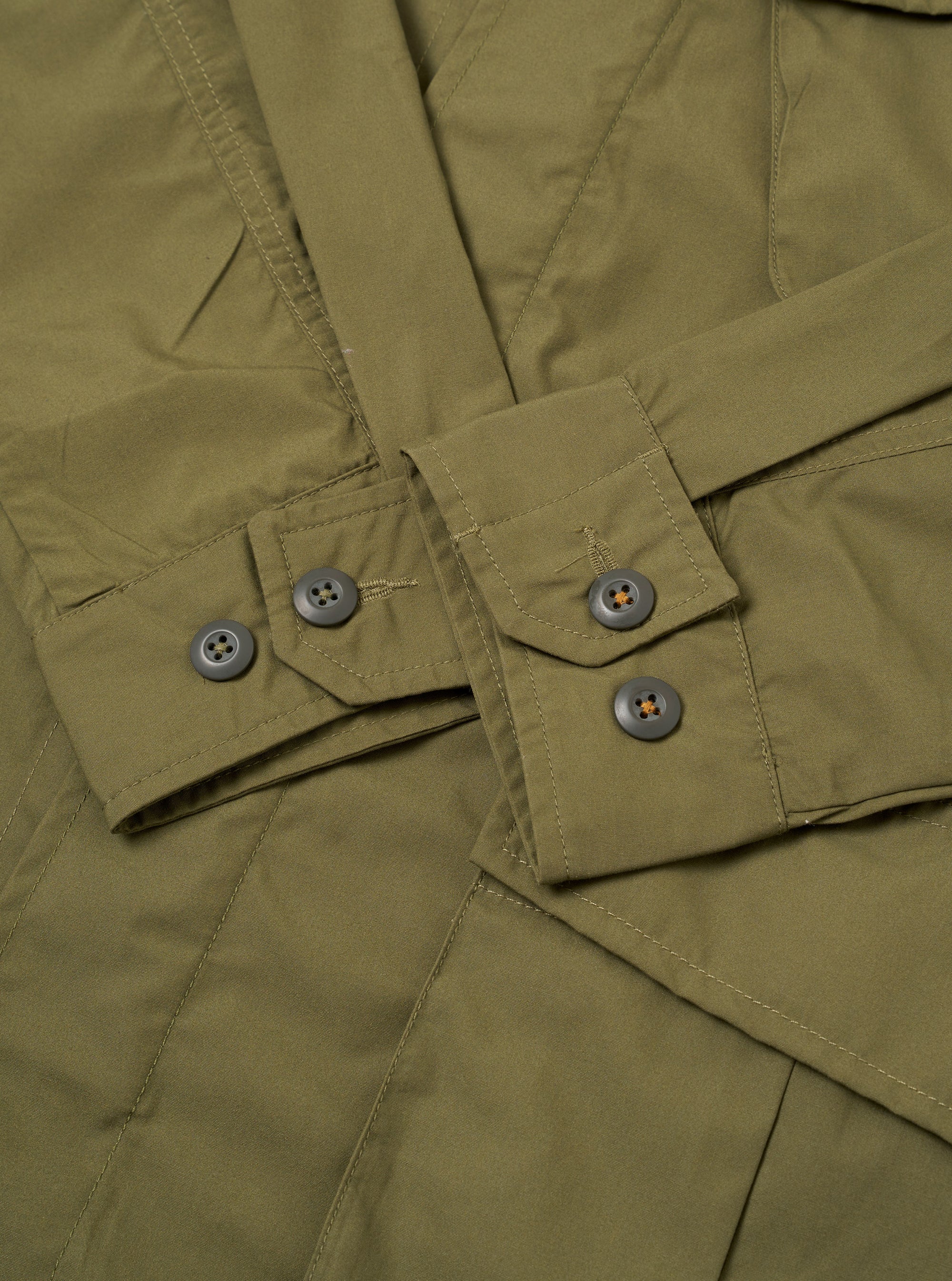 The Olive Recycled Polytech Jungle Jacket is shown from the back as a flat lay against a plain white background. The image highlights the horizontal back yoke and the clean, unstructured silhouette of the jacket.