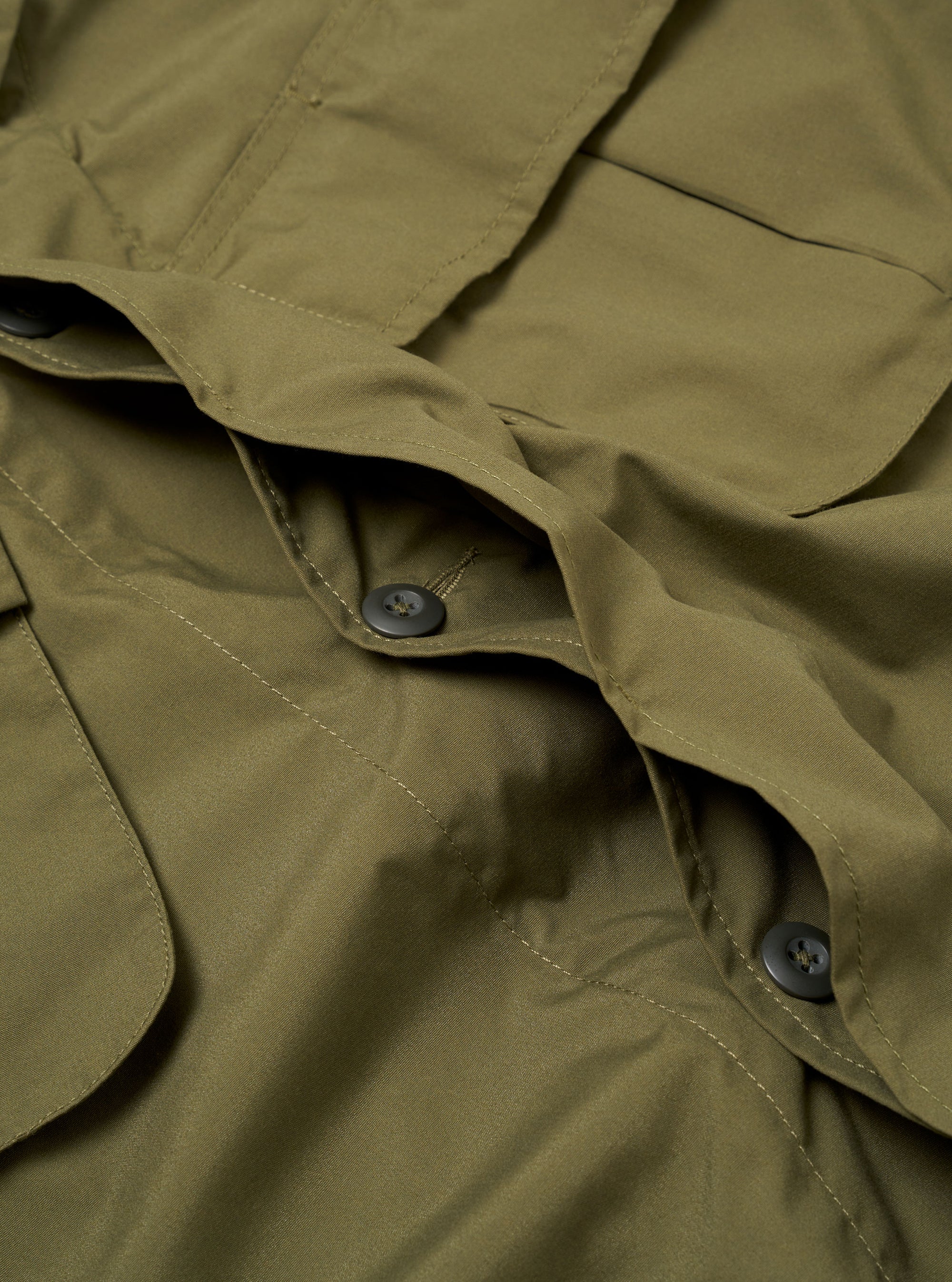 The Olive Recycled Polytech Jungle Jacket is shown in a detail view as a flat lay against a white background. This shot focuses on the upper section of the jacket, highlighting the structured collar, the top of the concealed button placket, and the two angled, pleated chest pockets with button-down flaps. The olive green fabric has a smooth, matte finish.