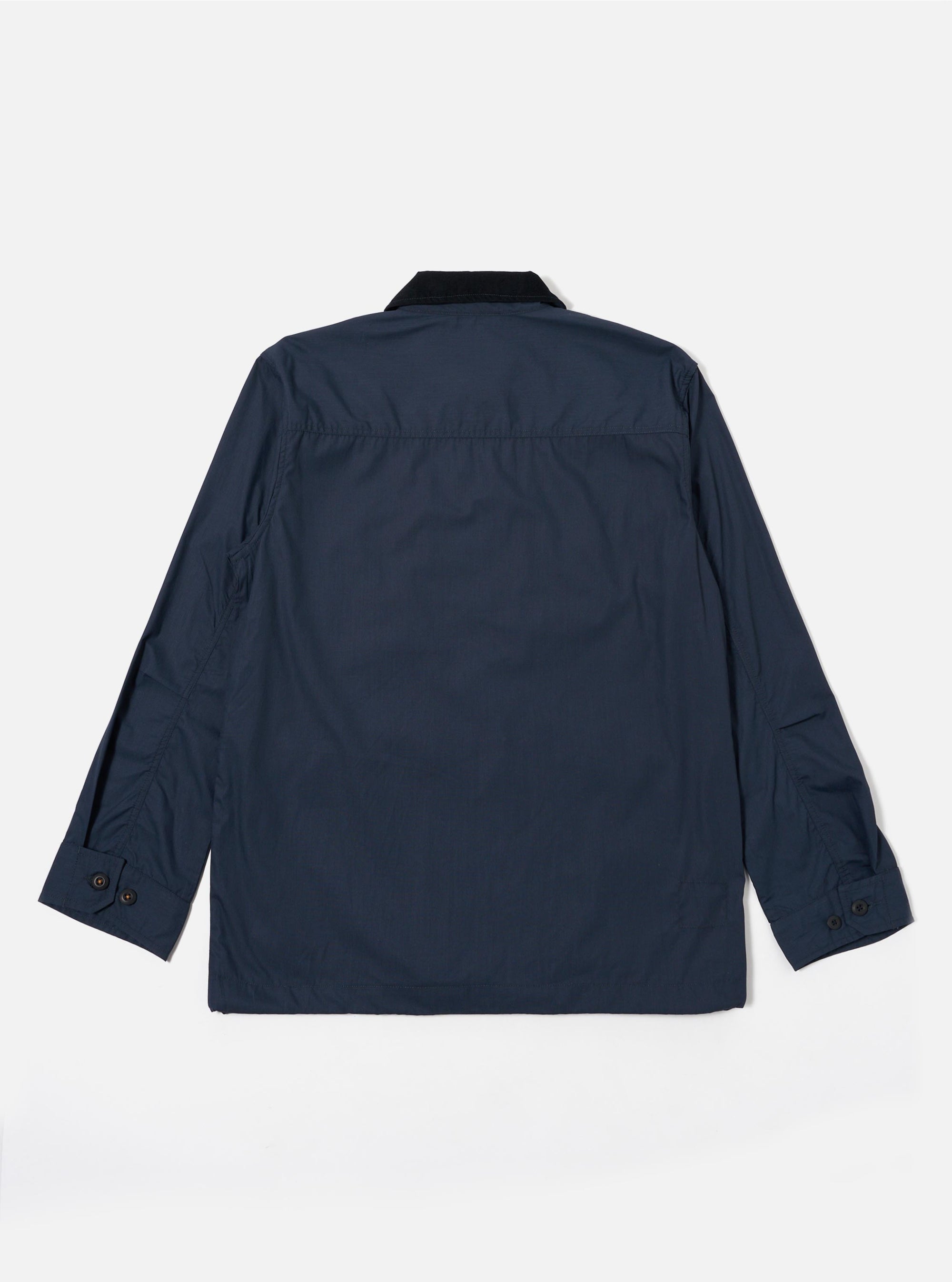 The Navy Recycled Polytech Parachute Field Jacket is shown from the back as a flat lay against a plain white background. The image highlights the smooth, dark navy technical fabric, the contrasting dark corduroy collar, and the adjustable drawcord visible at the straight hem. The long sleeves feature adjustable button cuffs.