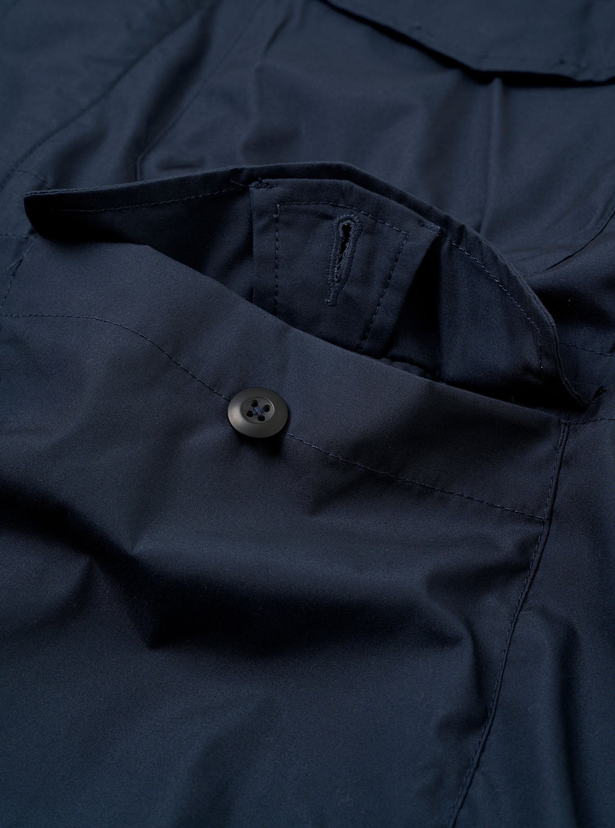 The Navy Recycled Polytech Parachute Field Jacket is shown from the back as a flat lay against a plain white background. The image highlights the jacket's smooth, dark navy fabric and its straight hem with an adjustable drawcord. A simple, horizontal yoke seam is visible across the upper back.