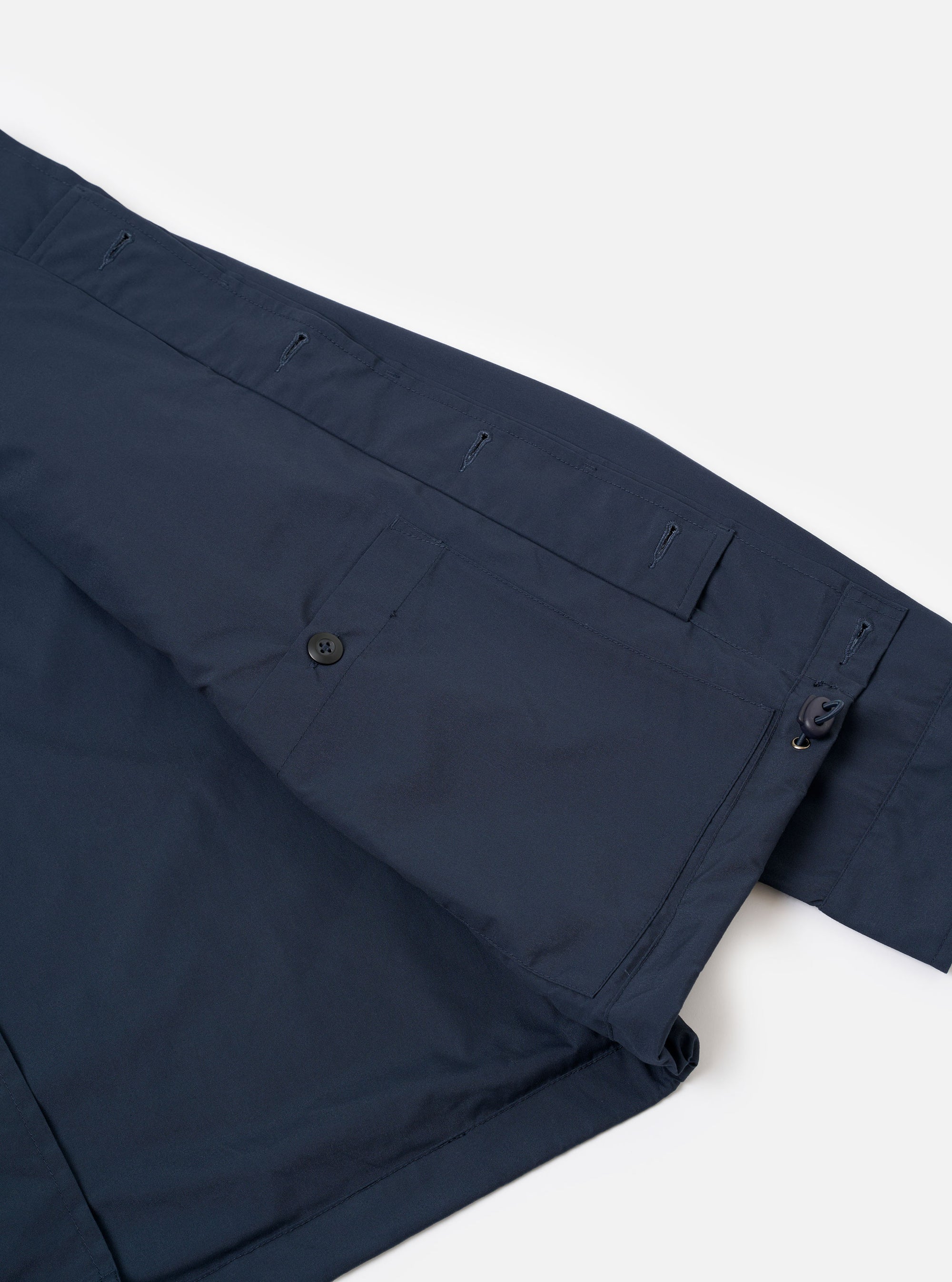 The Navy Recycled Polytech Parachute Field Jacket is shown from the back in a detail shot against a plain white background. The image highlights the adjustable drawcord hem and the smooth, technical texture of the navy blue recycled fabric.