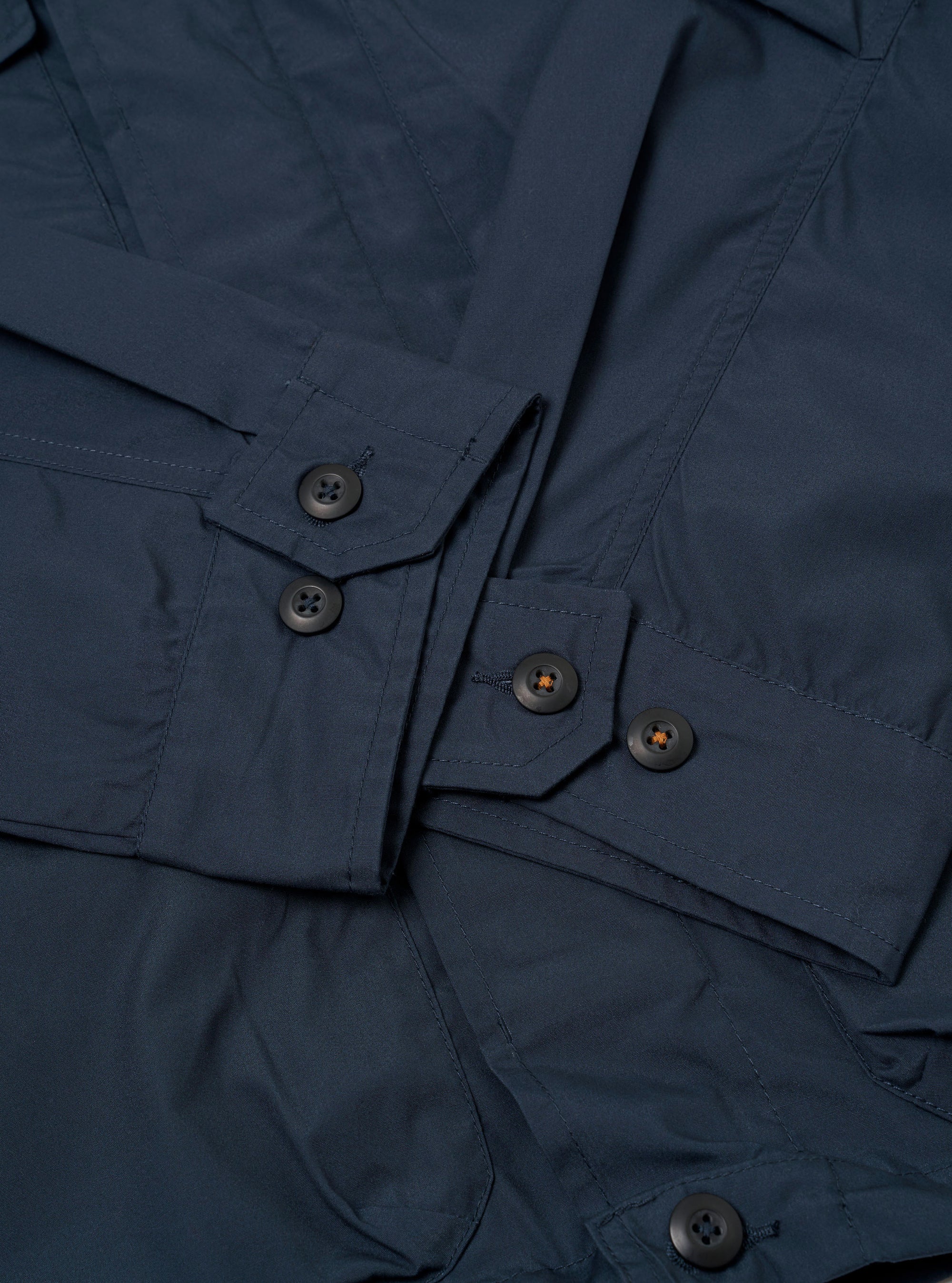 The Navy Recycled Polytech Parachute Field Jacket is shown from a rear angle as a flat lay against a plain white background. The image highlights the jacket's smooth navy blue fabric, a straight hem with an adjustable drawcord, and a contrasting brown corduroy collar.