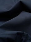 A close-up swatch of the Navy Recycled Polytech Parachute Field Jacket fabric displays a deep navy blue color with a smooth, technical texture. The compact woven material is shown in detail, filling the frame to highlight the utilitarian finish.