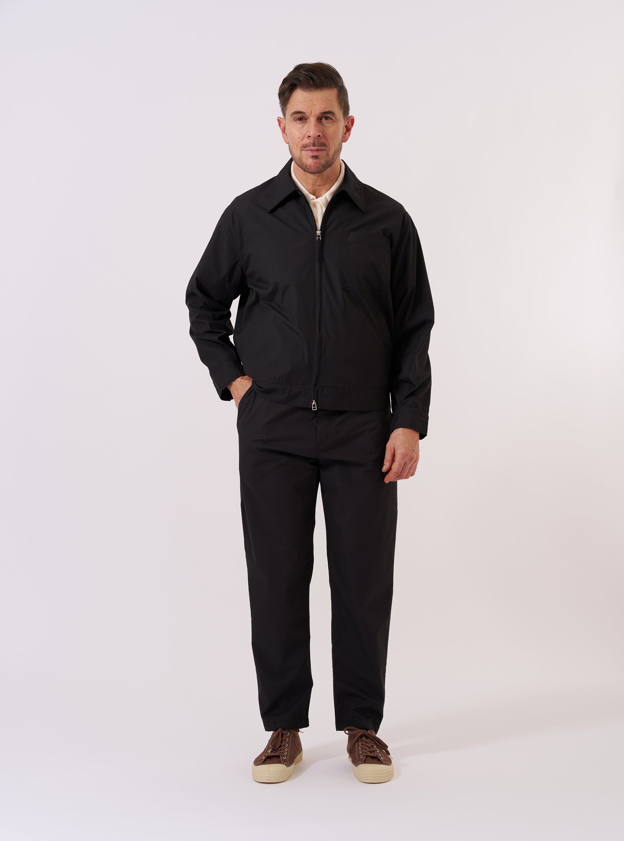 The Black Recycled Polytech Rose Bowl Jacket is shown as a flat lay against a white background. The jacket features a full-length two-way zipper, a classic collar, a single chest patch pocket, and two lower welt pockets. The black technical fabric has a smooth finish, and the garment is finished with buttoned cuffs and an adjustable back hem.