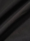 A close-up swatch image of the Black Recycled Polytech Rose Bowl Jacket highlights the smooth, technical texture of the black recycled polytech fabric. The material fills the frame, providing a detailed view of the garment's color and construction.