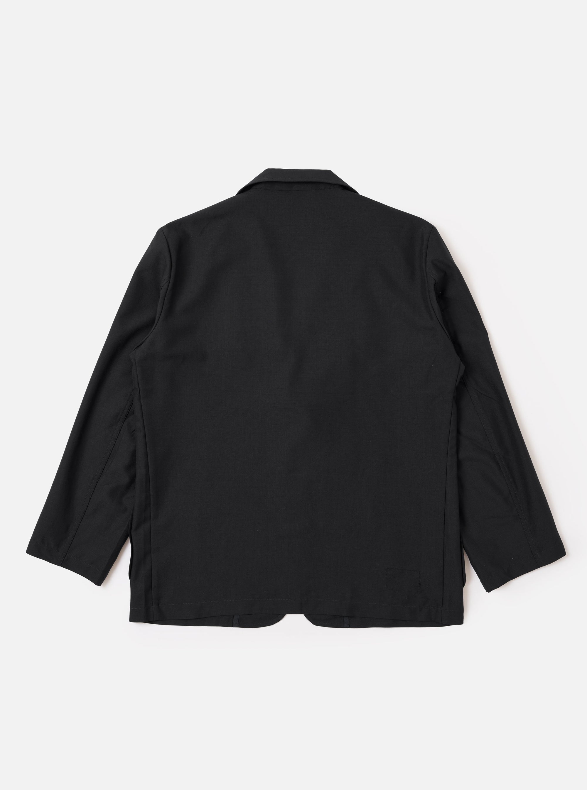 The Black Tropical Suiting Two Button Jacket is shown from the back as a flat lay against a plain white background. The image highlights the clean lines of the relaxed fit, the shaping through the waist, and the two-piece sleeve construction.