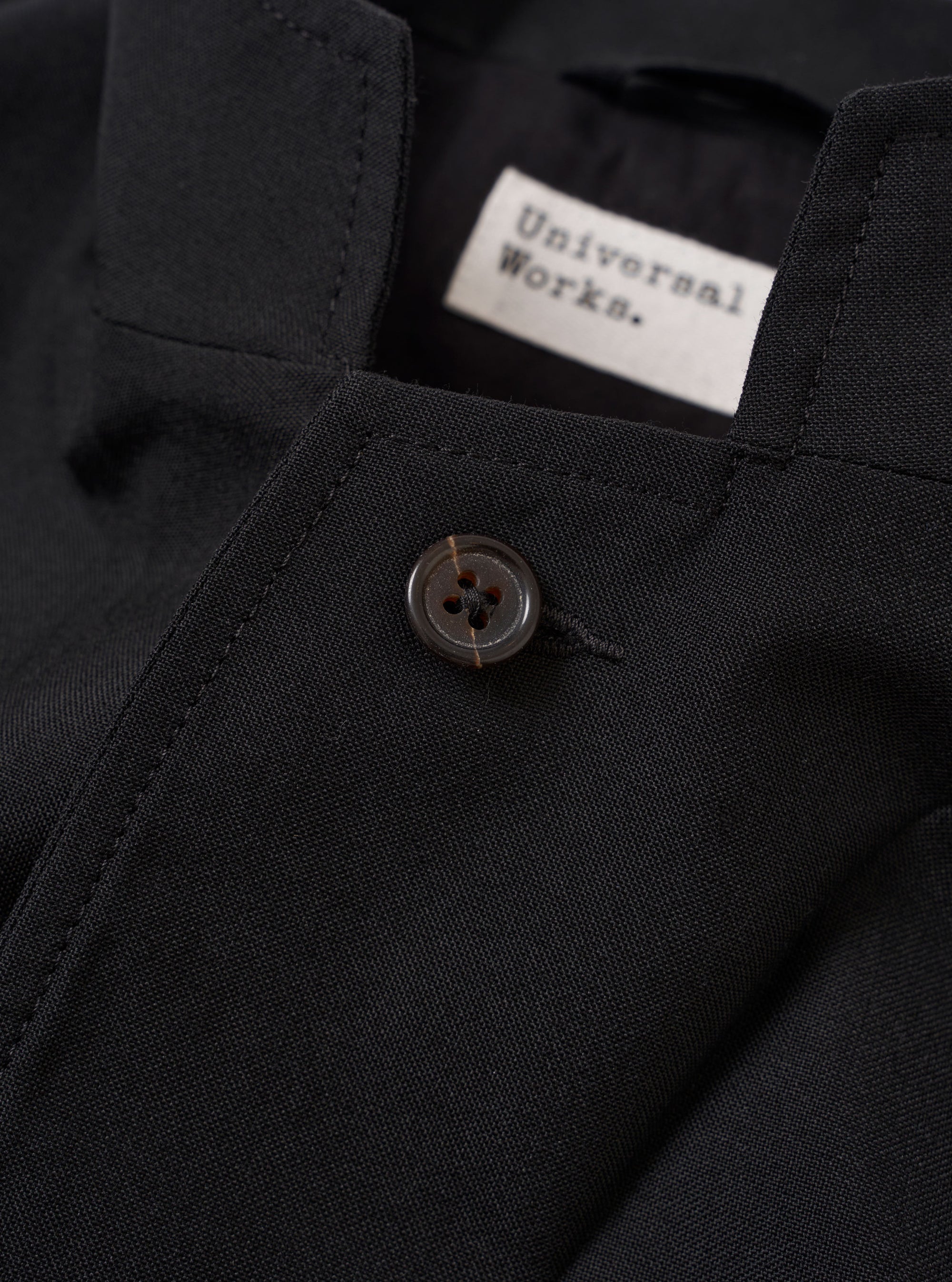 The Black Tropical Suiting Two Button Jacket is shown from the back as a flat lay against a plain white background. The image highlights the jacket’s clean tailoring, featuring a centered rear vent and visible vertical seams. The fabric has a smooth, lightweight appearance characteristic of tropical suiting.