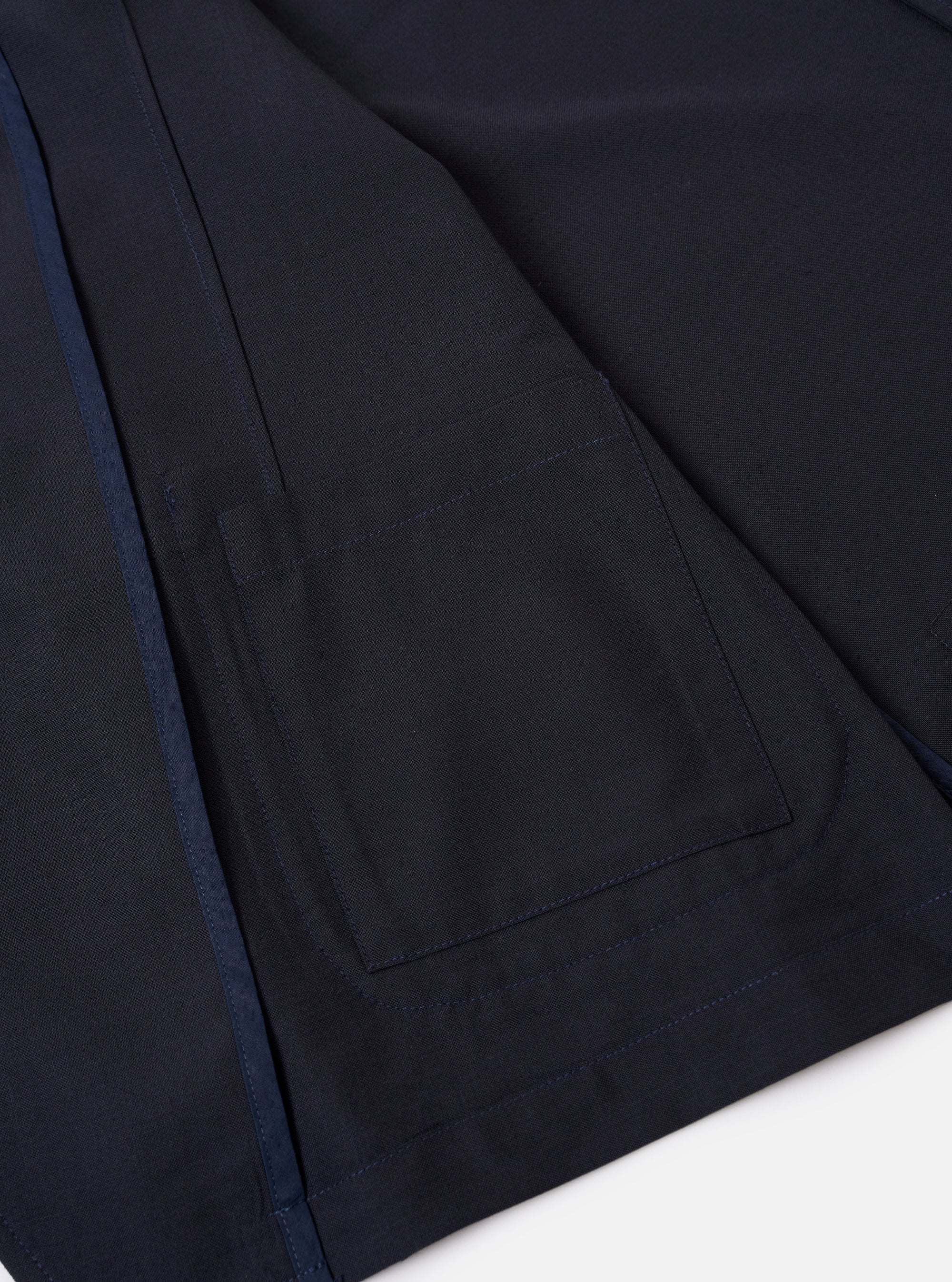 The Navy Tropical Suiting Two Button Jacket is displayed as a flat lay against a plain white background. The jacket features a relaxed, unstructured fit with a two-button front closure and a long, wide notch lapel. Three patch pockets are visible on the front: one at the chest and two larger pockets at the waist. The garment is made from a smooth, lightweight navy blue tropical suiting fabric.