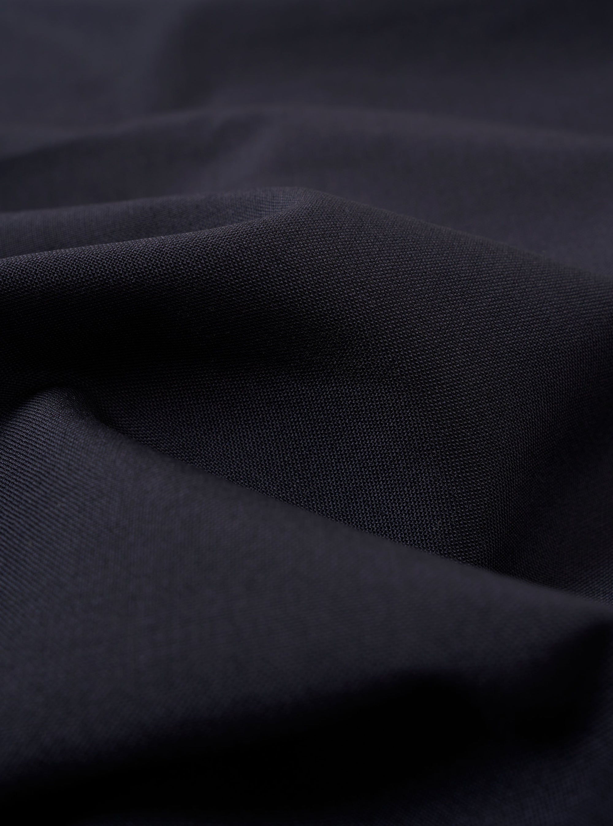 The Navy Tropical Suiting Military Chino is shown as a flat lay against a white background. The image highlights the side profile of the trousers, showcasing the waistband with belt loops, the side pocket, and the clean, straight leg. The fabric is a smooth, dark navy tropical suiting material.