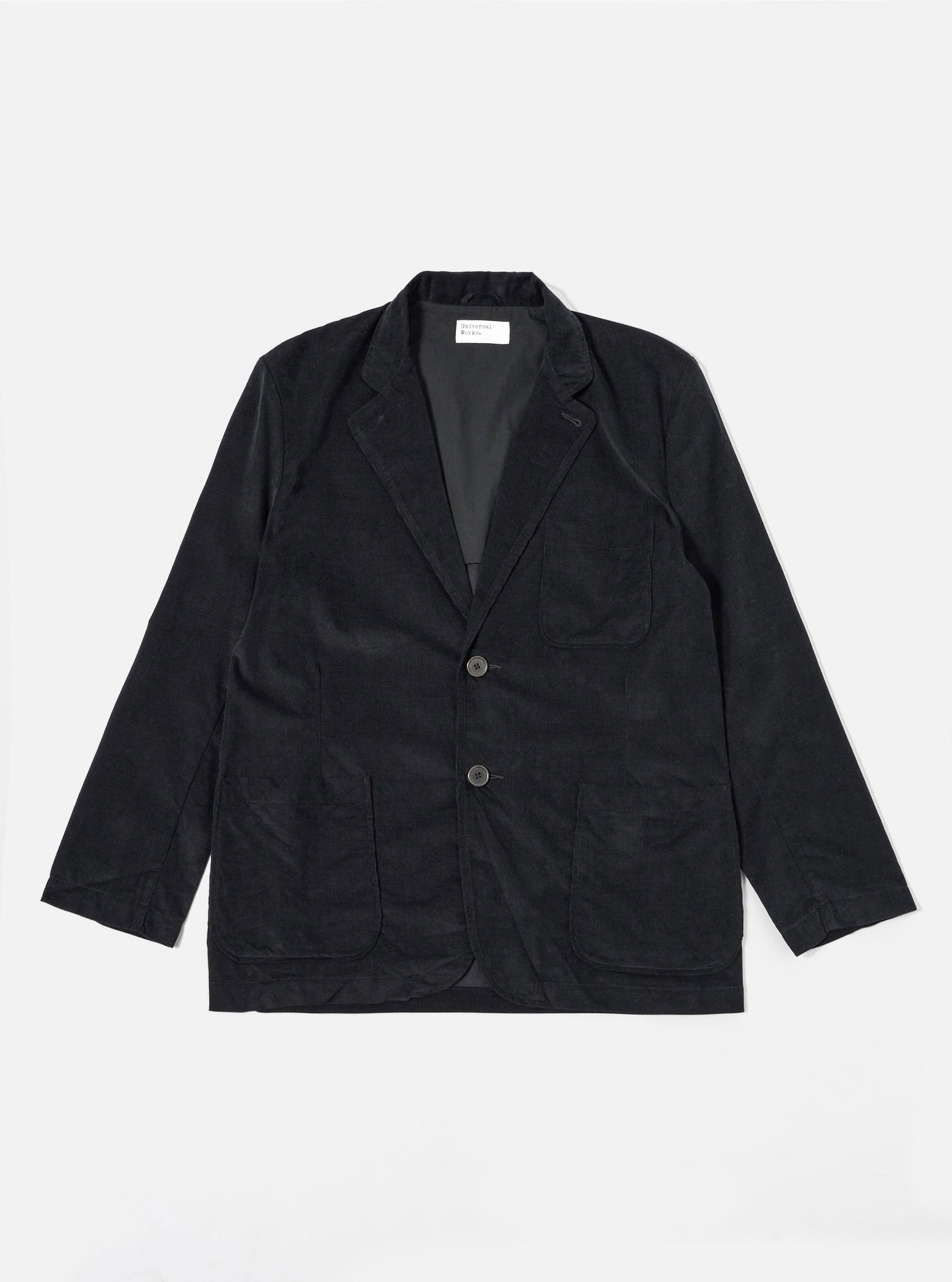 The Black Organic Fine Cord Two Button Jacket is shown as a flat lay against a white background. The jacket features a classic two-button front closure, a notch lapel, and two large patch pockets at the waist with a single chest patch pocket. The fine-wale organic cotton corduroy fabric provides a subtle vertical texture to the solid black garment.