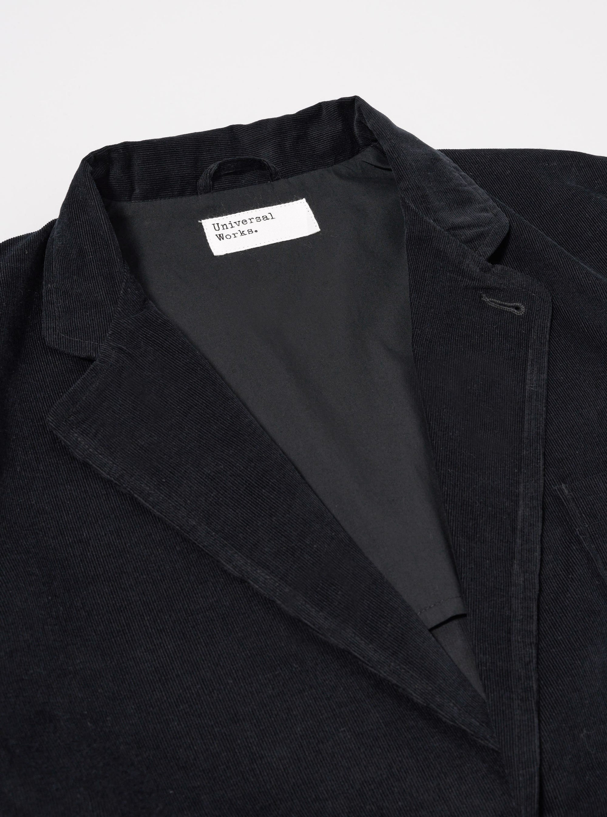 The Black Organic Fine Cord Two Button Jacket is shown from the back as a flat lay against a plain white background. The jacket features a contemporary, relaxed fit with a fine corduroy texture throughout. The rear view highlights the clean construction and the two-piece sleeve design.