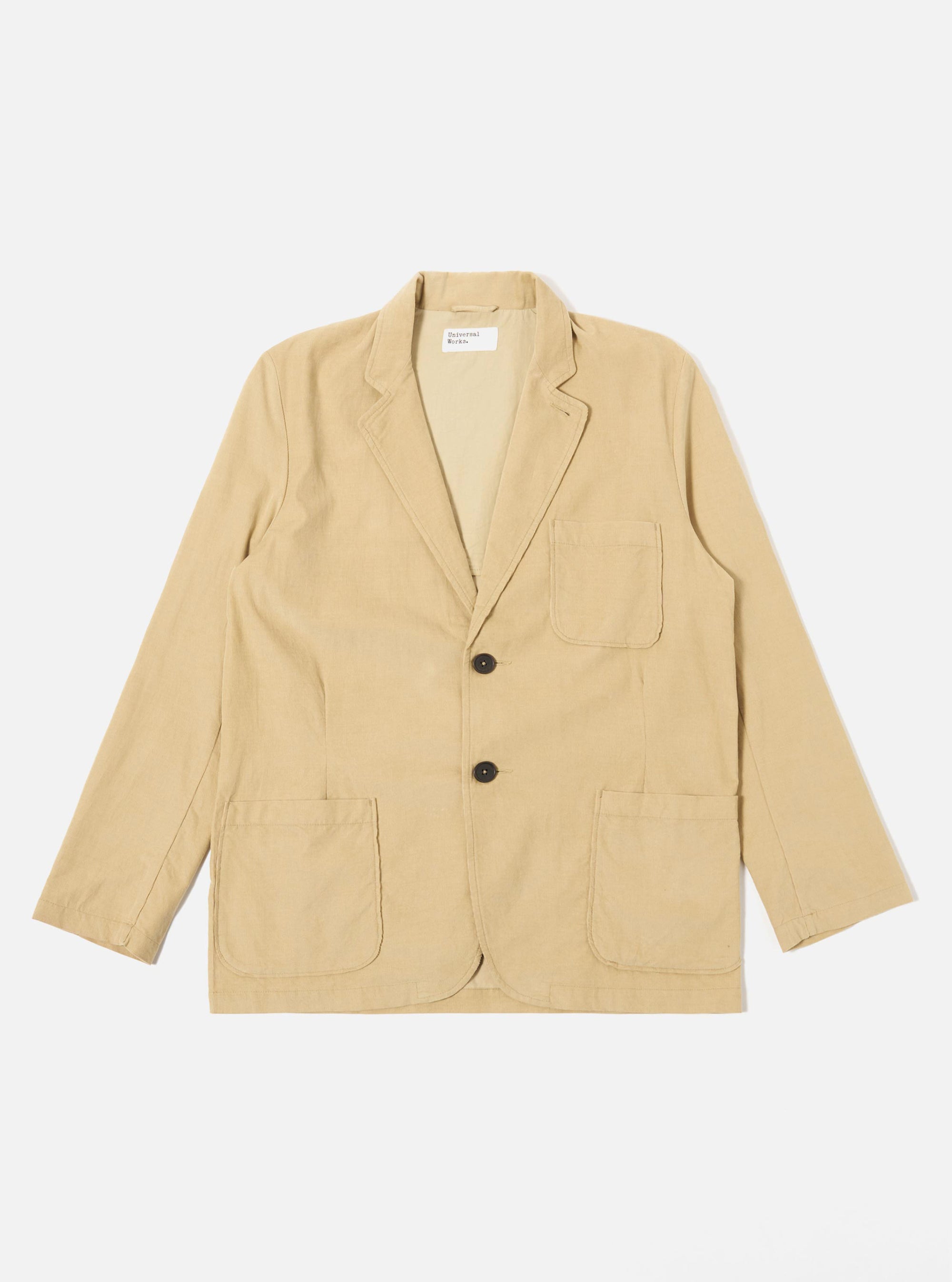 The Sand Organic Fine Cord Two Button Jacket is displayed as a flat lay against a plain white background. The jacket features a two-button front closure, a long and wide notched lapel, one chest patch pocket, and two larger patch pockets at the waist. The fine-wale organic cotton corduroy fabric has a visible vertical ribbed texture in a light sand color.