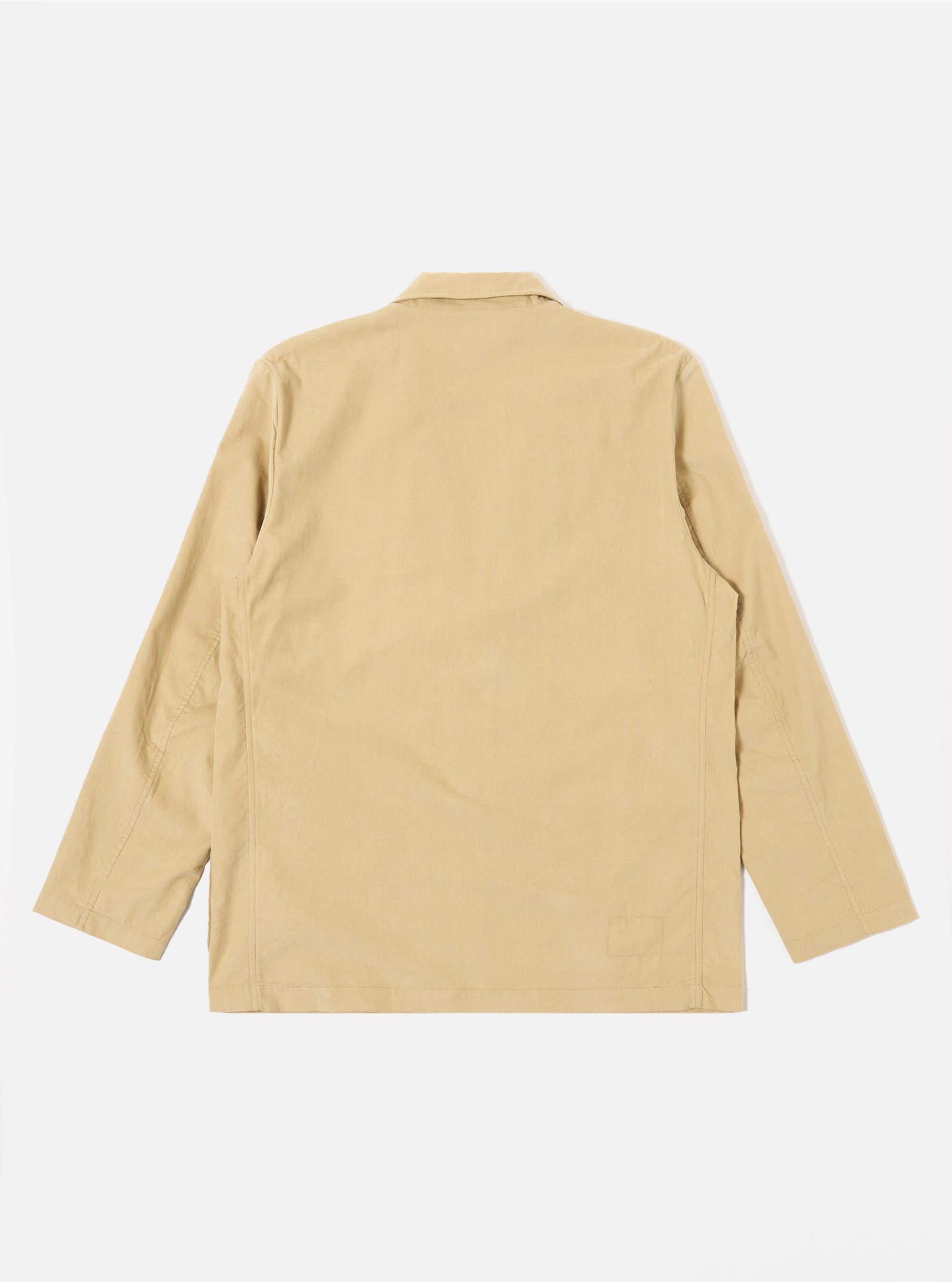 The Sand Organic Fine Cord Two Button Jacket is shown from the back as a flat lay against a plain white background. The image highlights the clean, simple construction of the jacket's rear, featuring a central vertical seam and a straight hem. The fine corduroy texture of the sand-colored organic cotton is visible.