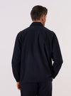 A model wears the Dark Navy Ospina Cotton Two Button Jacket, shown from the back against a plain white background. The jacket features a clean back panel with a central rear vent and a straight hem. The dark navy fabric highlights a distinct puckered seersucker texture throughout.