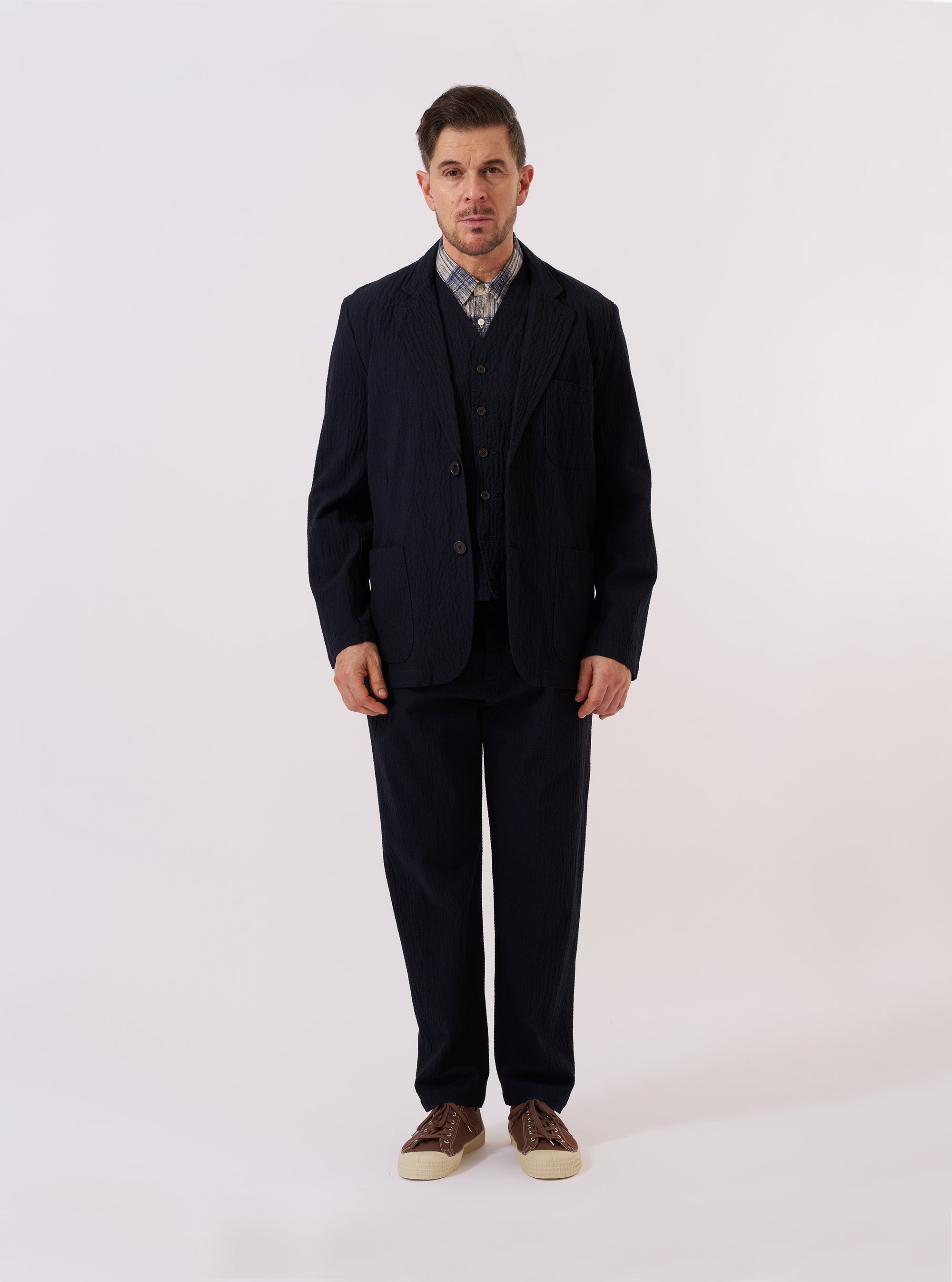 The Dark Navy Ospina Cotton Two Button Jacket is shown as a flat lay against a plain white background. The jacket features a two-button front closure, a long, wide lapel, and three patch pockets, including one chest pocket and two larger pockets at the waist. The dark navy fabric has a visible puckered seersucker texture.