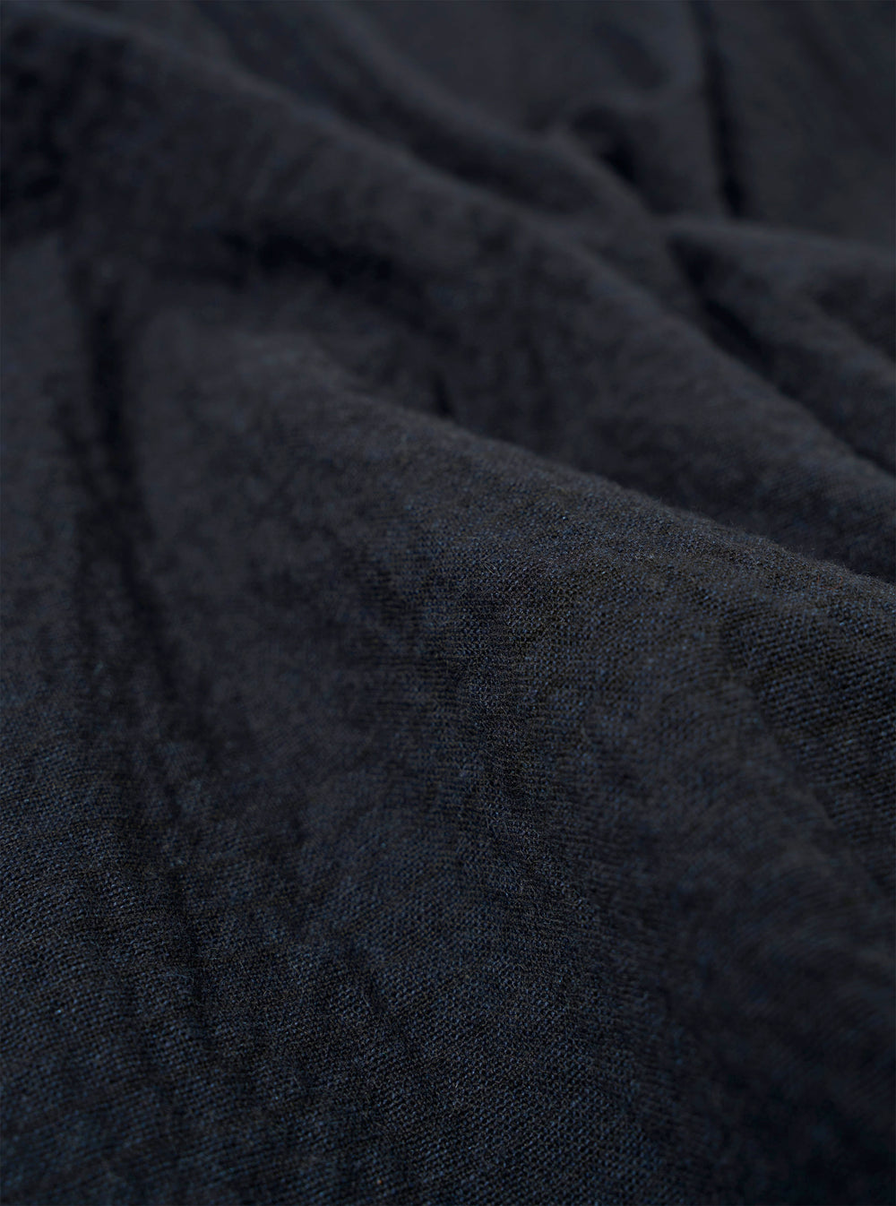 A close-up fabric swatch of the Dark Navy Ospina Cotton Two Button Jacket highlights the deep navy blue color and the distinct puckered texture of the seersucker fabric. The material fills the frame, providing a detailed view of the garment's weave and construction.