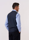 A model is wearing the Navy Recycled Polytech City Waistcoat over a light-colored long-sleeve top. The model is shown from a side-angle view against a plain white background. The waistcoat features a button-down front, a V-neckline, and a large patch pocket visible on the side. The garment is constructed from a dark navy recycled polytech fabric with a smooth finish.