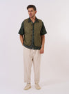 The Olive Recycled Polytech City Waistcoat is presented as a flat lay against a plain white background. The waistcoat features a v-neck, a central button-front closure, and three front patch pockets. The fabric is a solid olive green.