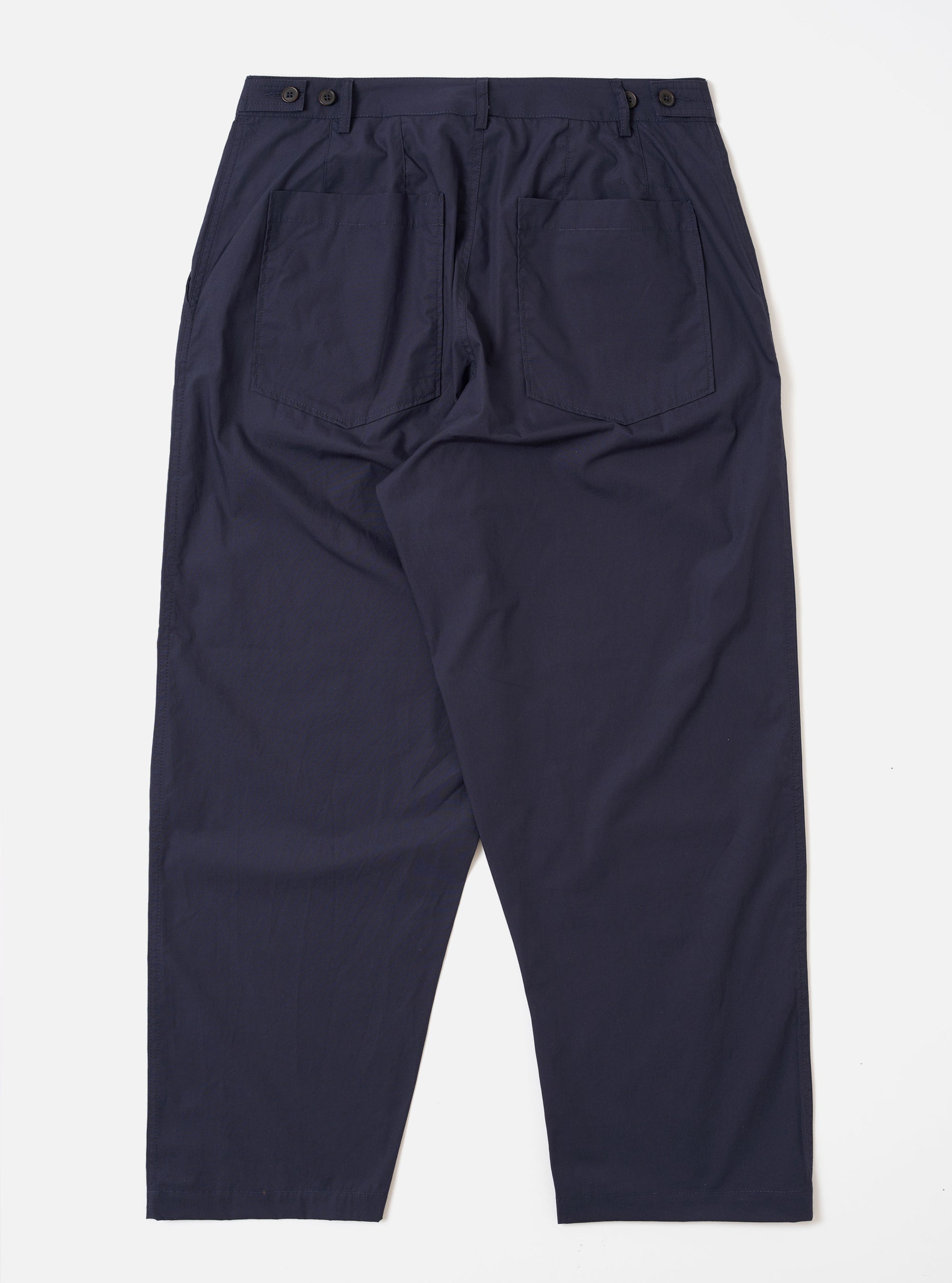The Navy Peached Poplin Dutch Pant is shown from the back as a flat lay against a white background. The image highlights the loose, wide-leg fit and features two large rear patch pockets with button closures and a visible brand label above the right pocket.